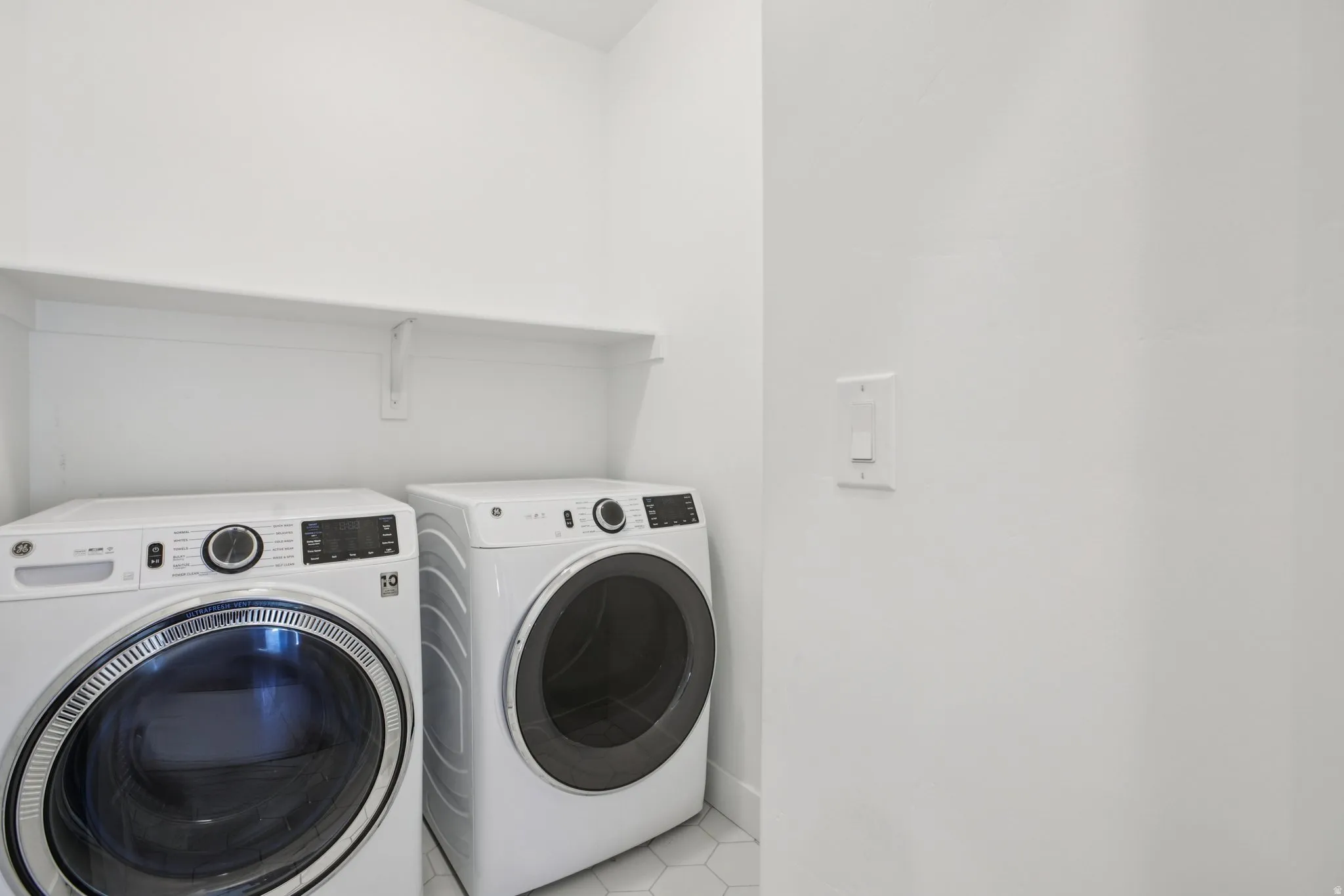 Laundry area with light tile patterned floors and washer and clothes dryer
