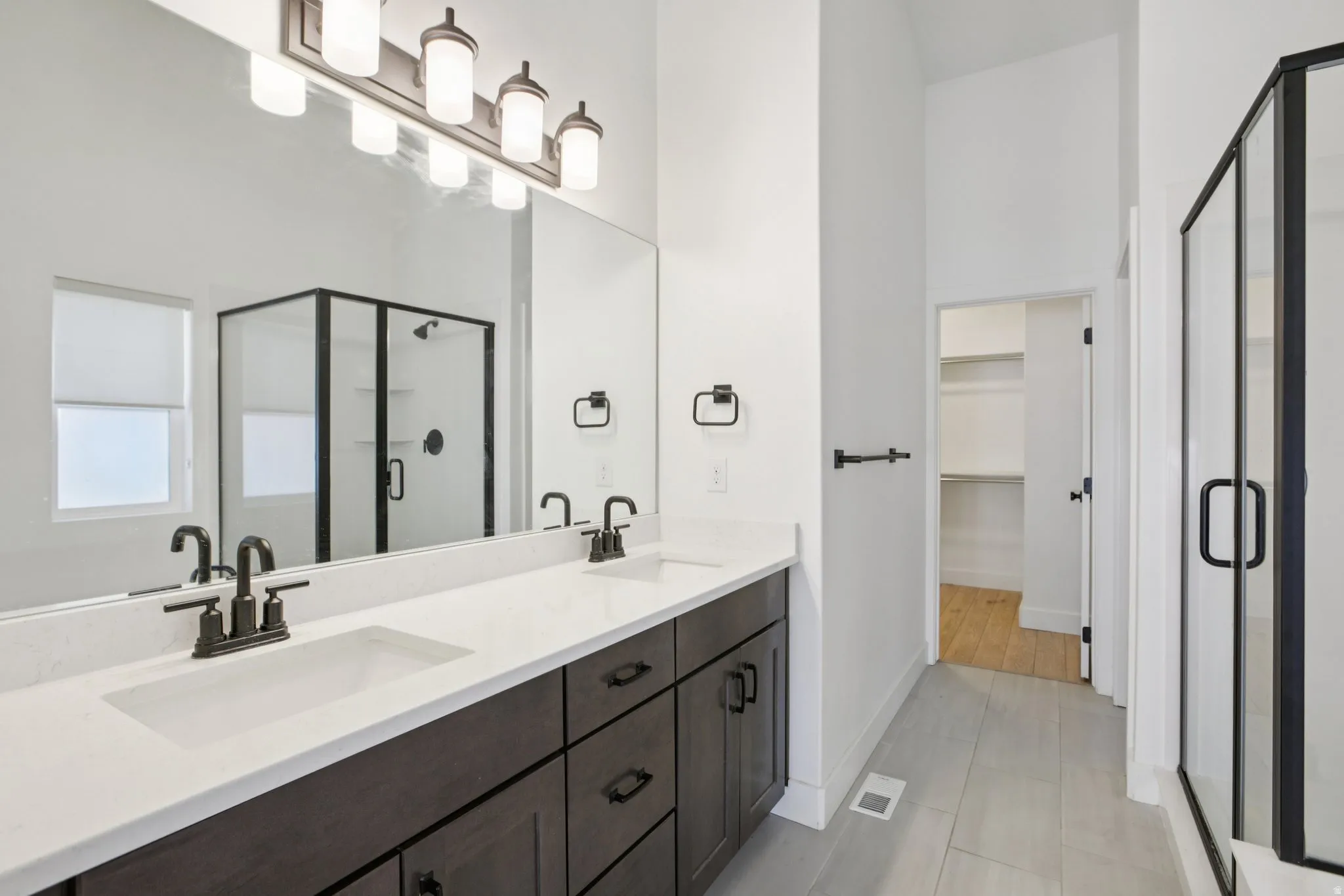 Full bathroom with a shower stall, double vanity, and a spacious closet