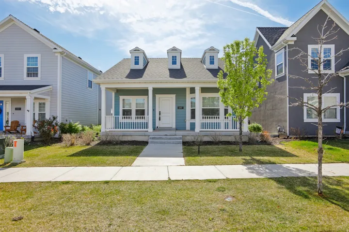 View of front of house with covered porch, roof with shingles, and a front lawn