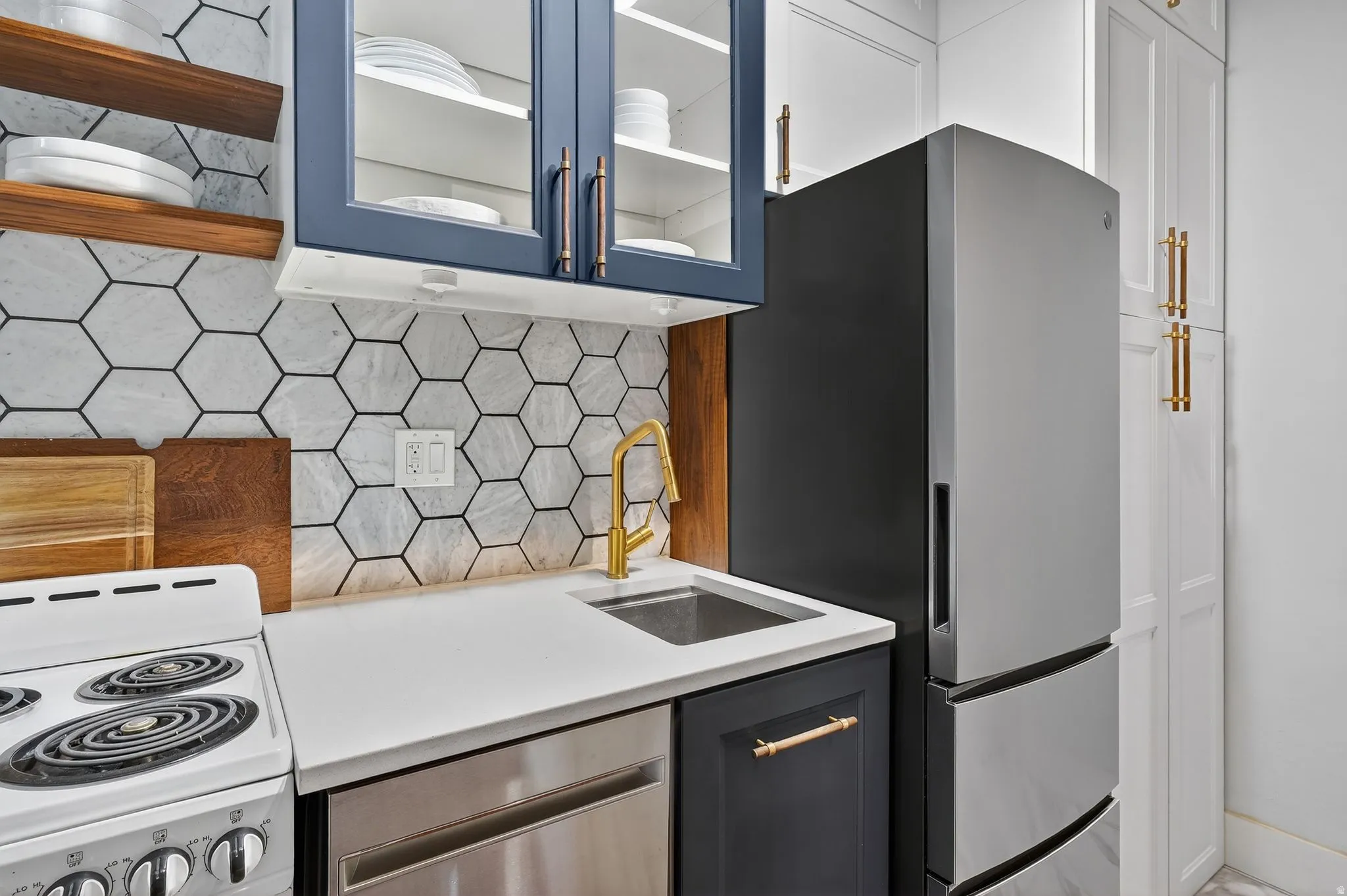 Kitchen featuring stainless steel appliances, decorative backsplash, glass insert cabinets, and light stone counters