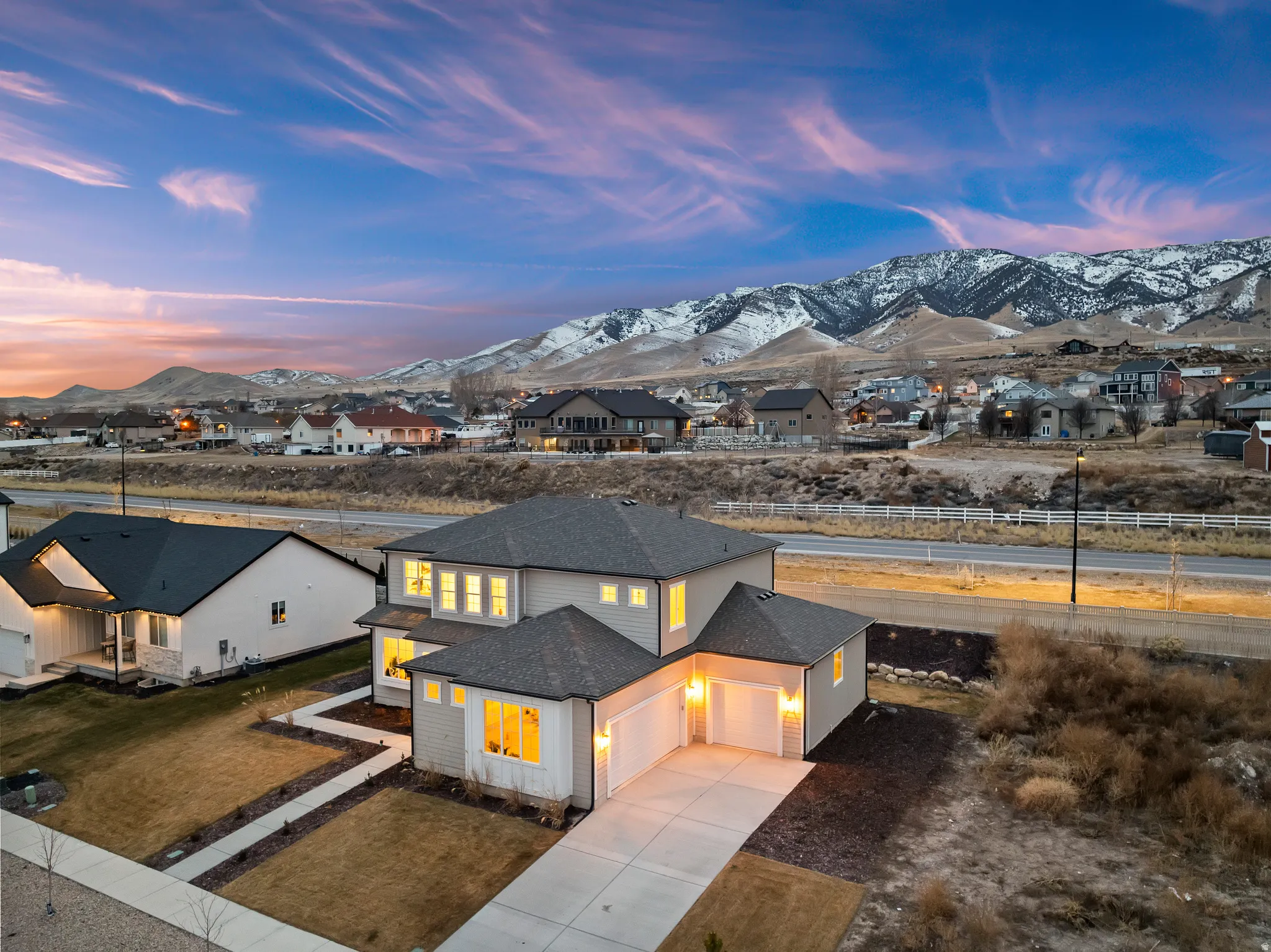 View of front of property with a mountain view, roof with shingles, driveway, a residential view, and a garage