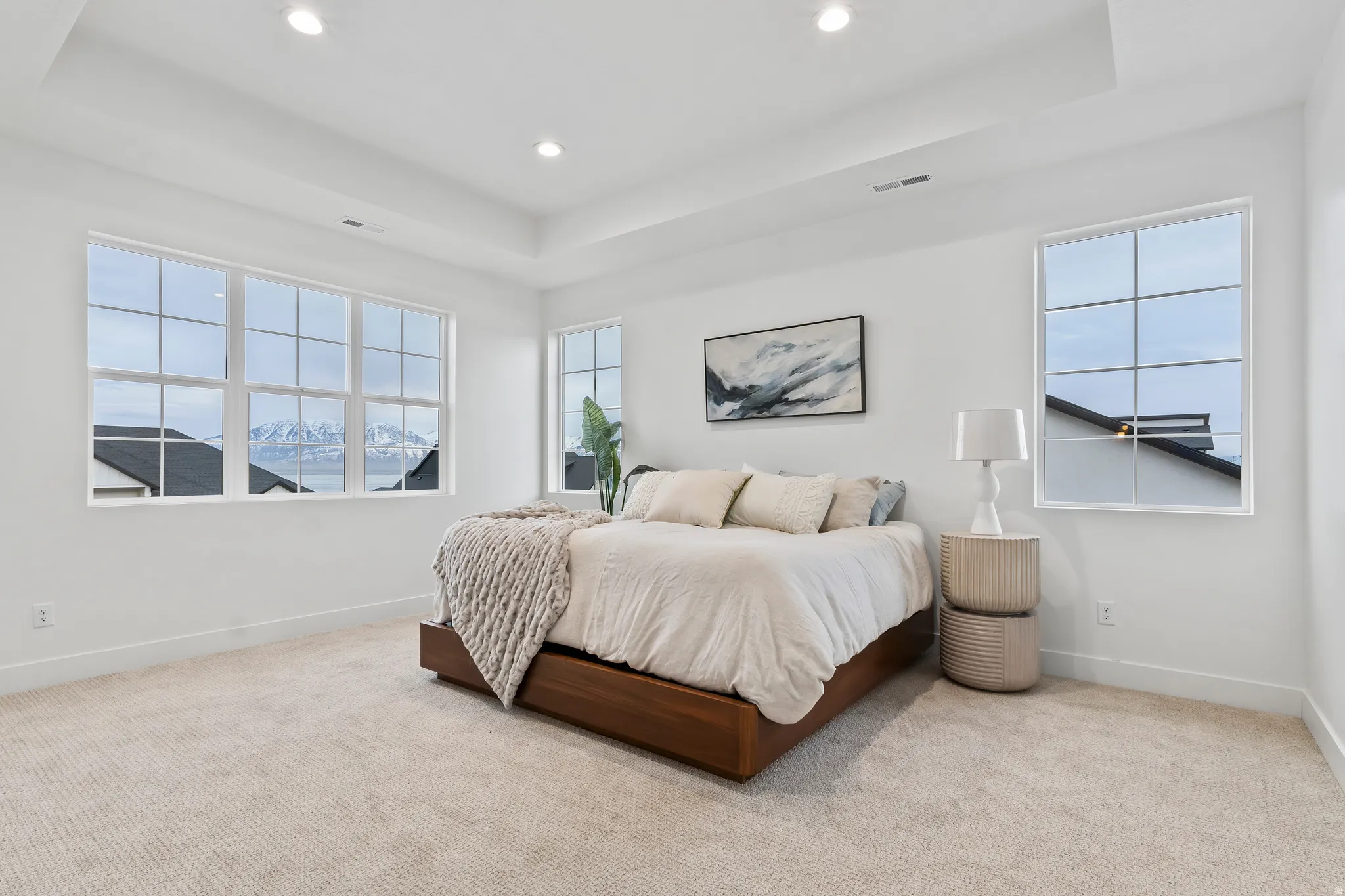 Bedroom with a raised ceiling, light colored carpet, and recessed lighting