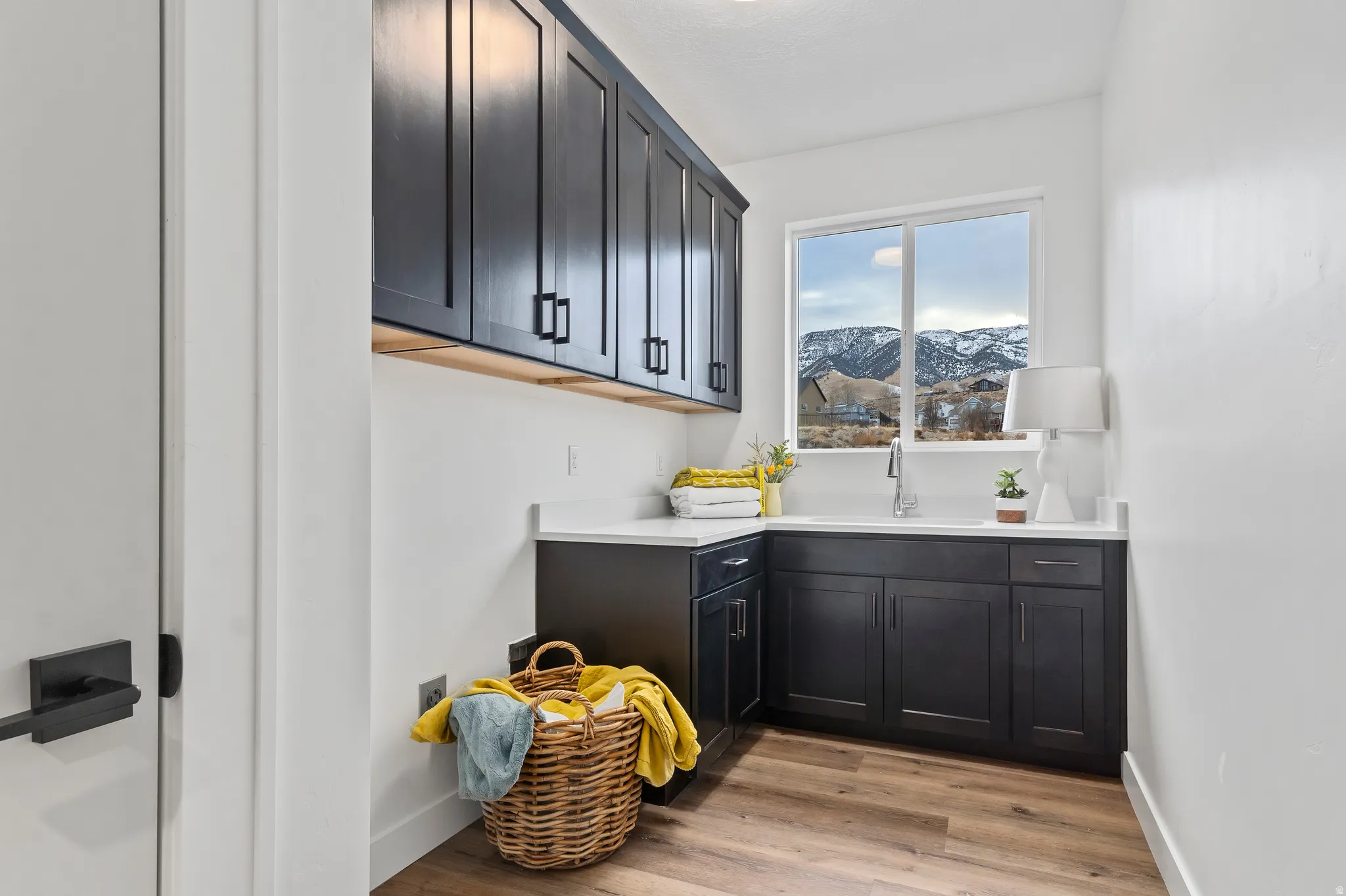 Bar with a mountain view, dark cabinetry, light wood finished floors, and light stone counters