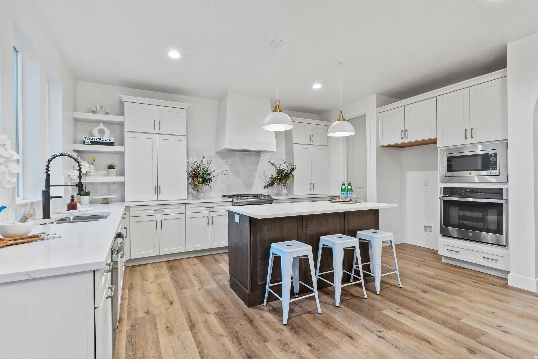 Kitchen with stainless steel appliances, a center island, a breakfast bar area, light wood-style floors, and open shelves