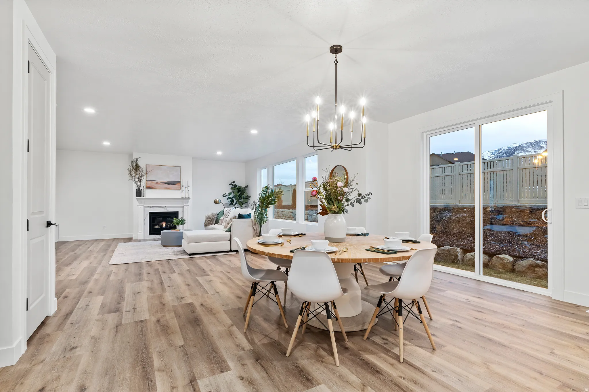 Dining area with light wood-style floors, a fireplace, and suspended lighting