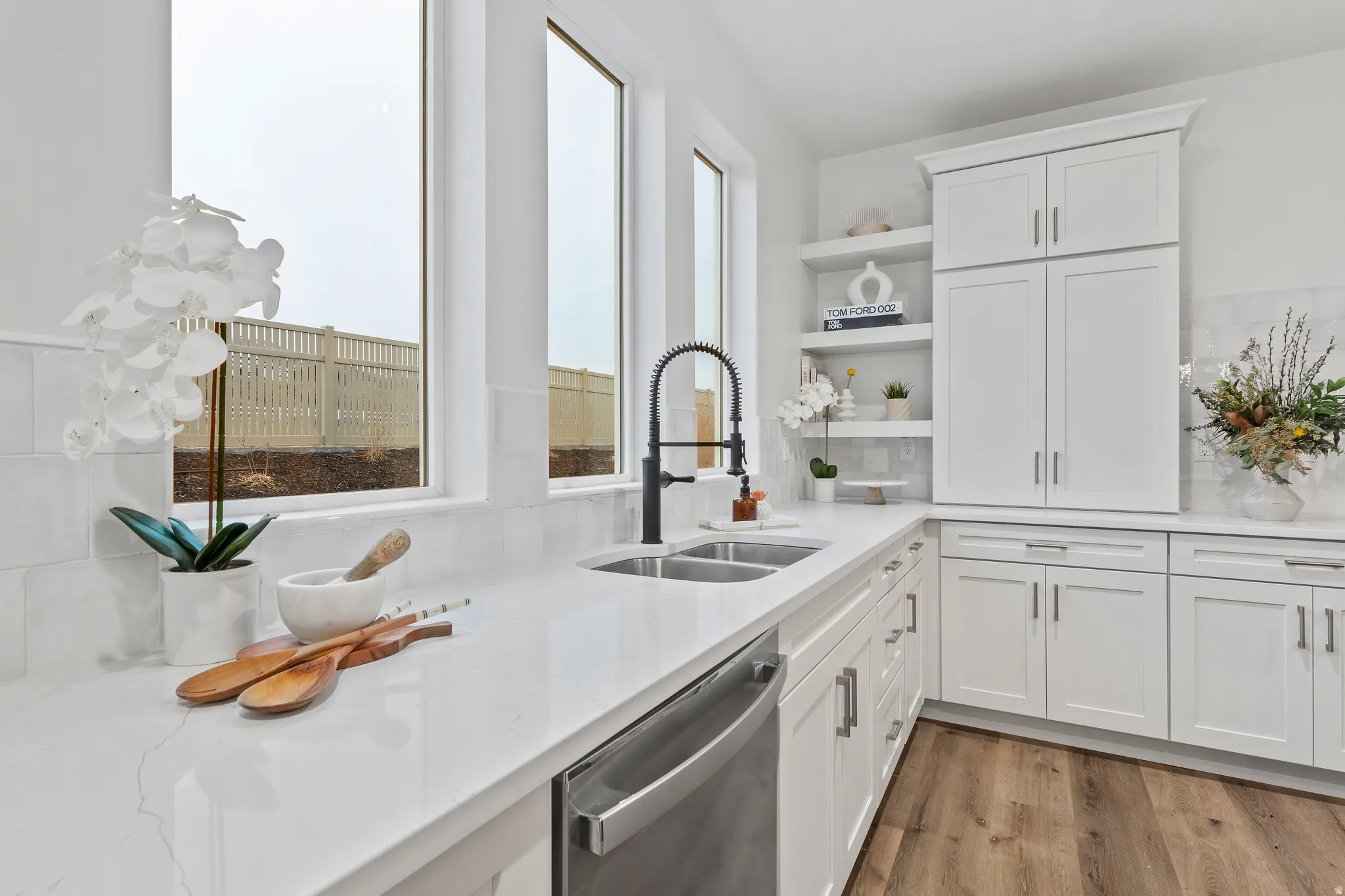 Kitchen featuring white cabinetry, open shelves, stainless steel dishwasher, and decorative backsplash