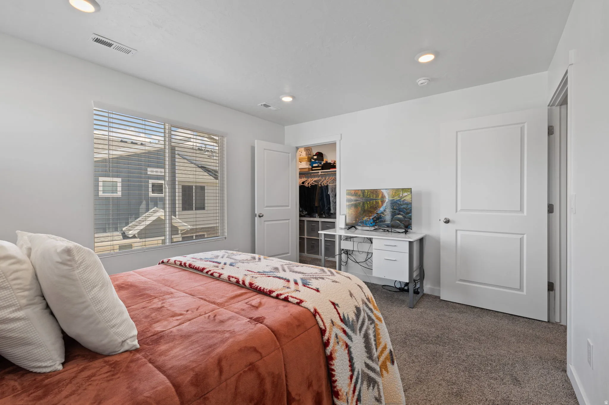 Bedroom with dark carpet, a walk in closet, and recessed lighting