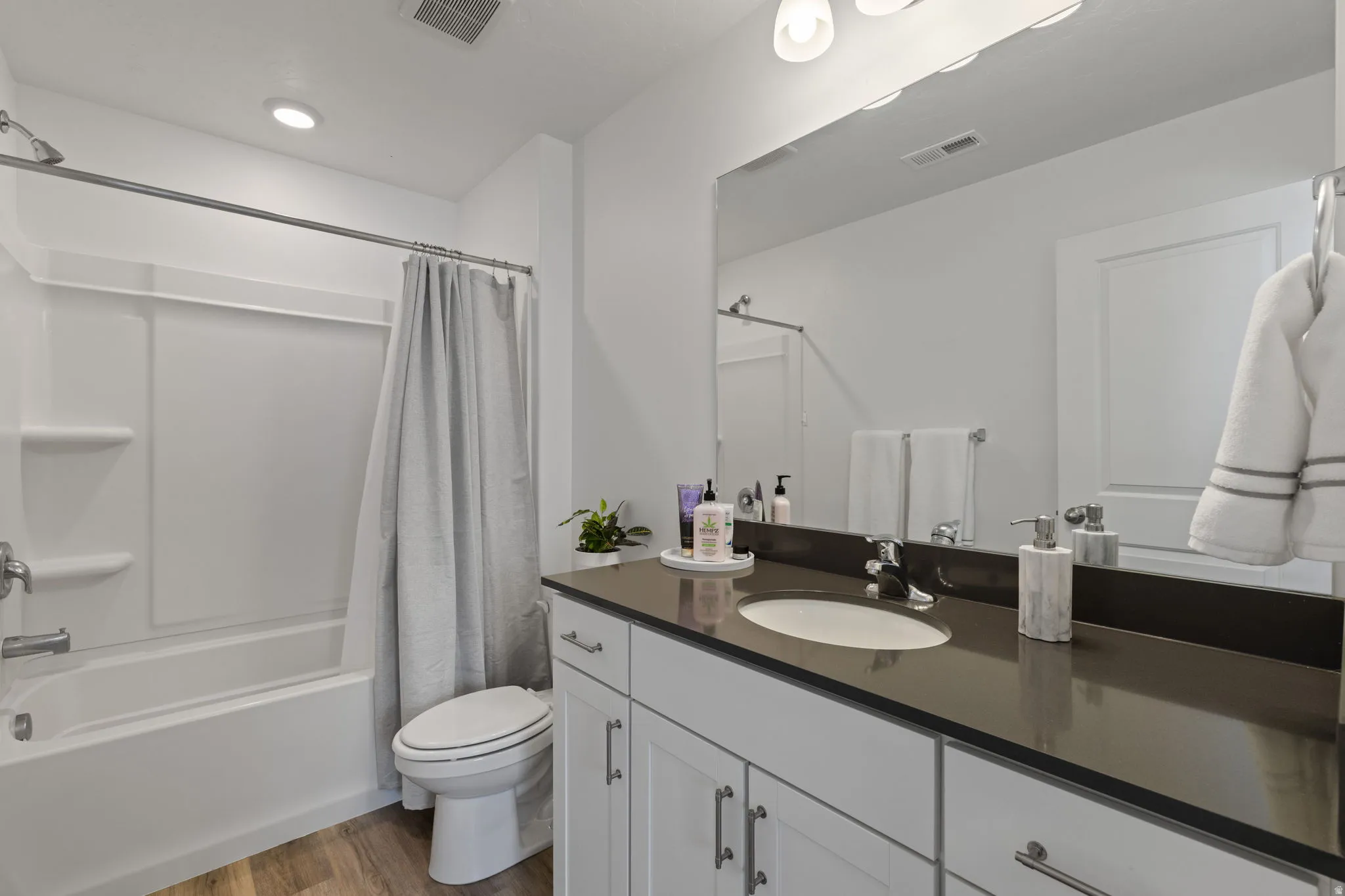 Bathroom featuring vanity, dark wood-style flooring, and shower / bath combo with shower curtain