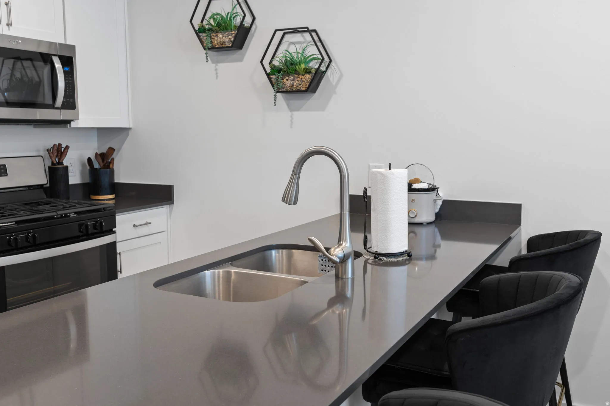 Kitchen with white cabinetry, stainless steel appliances, a kitchen bar, and dark stone counters