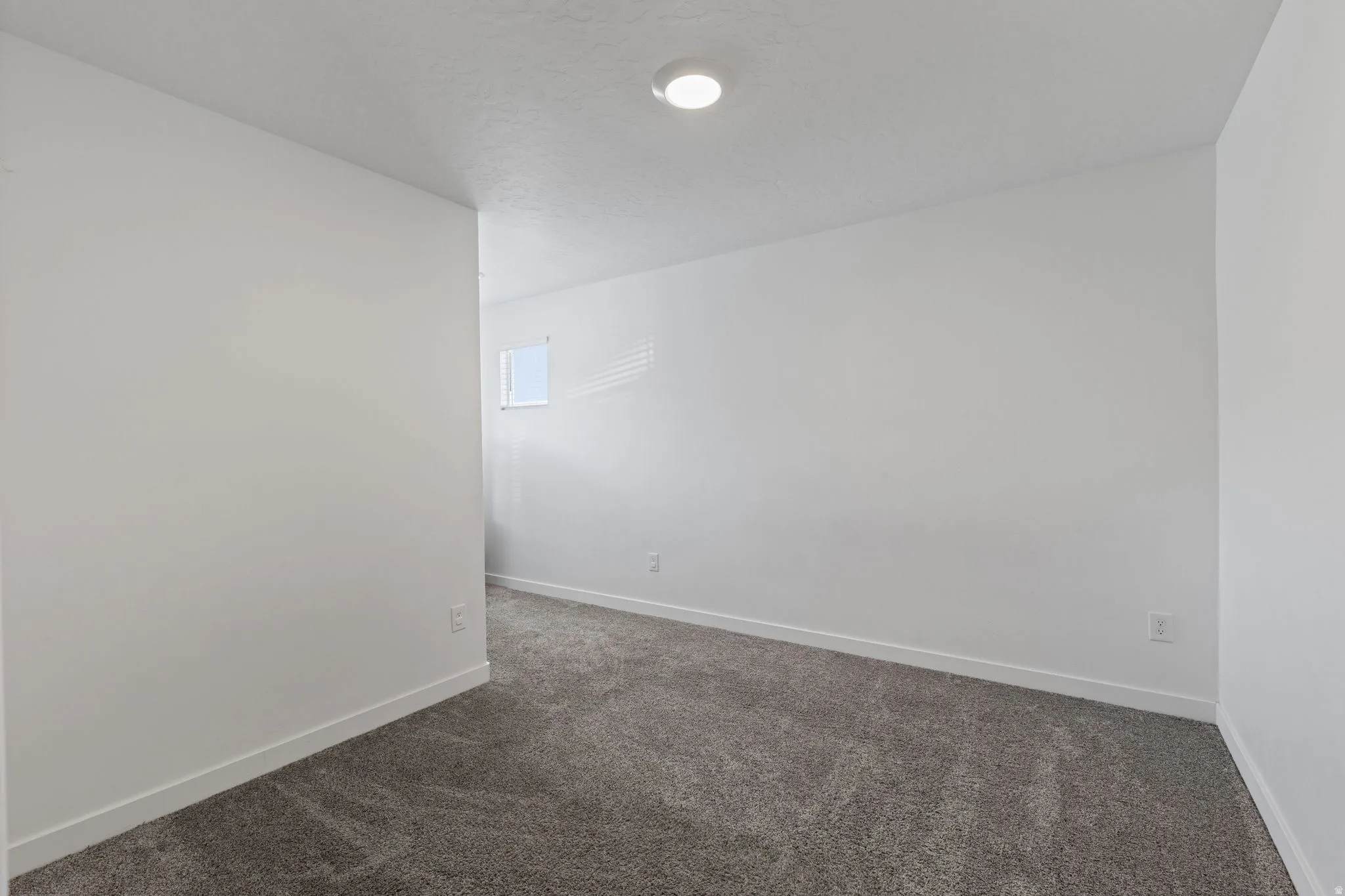 Unfurnished room with dark colored carpet and baseboards