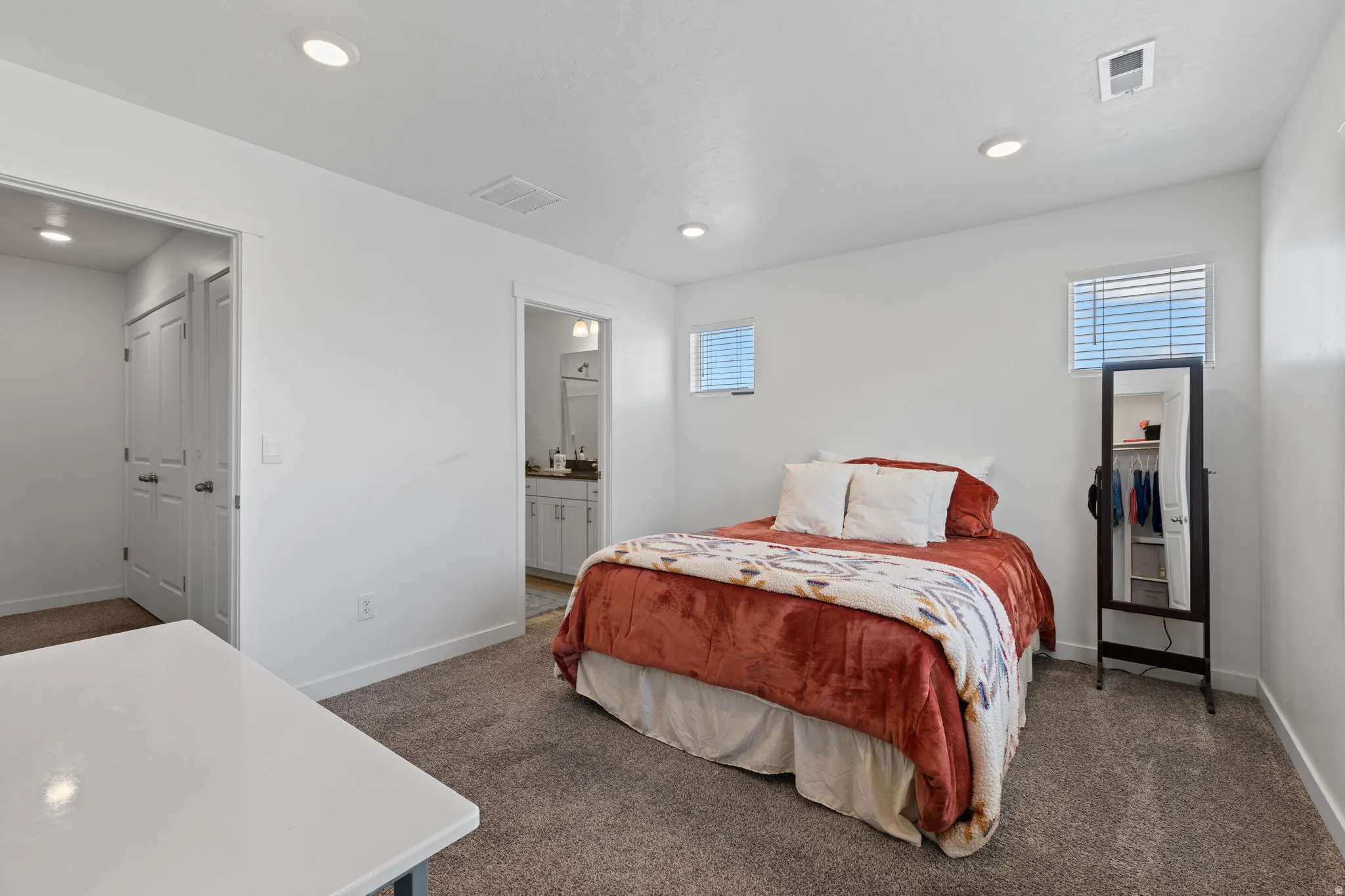 Bedroom featuring dark carpet, recessed lighting, and connected bathroom