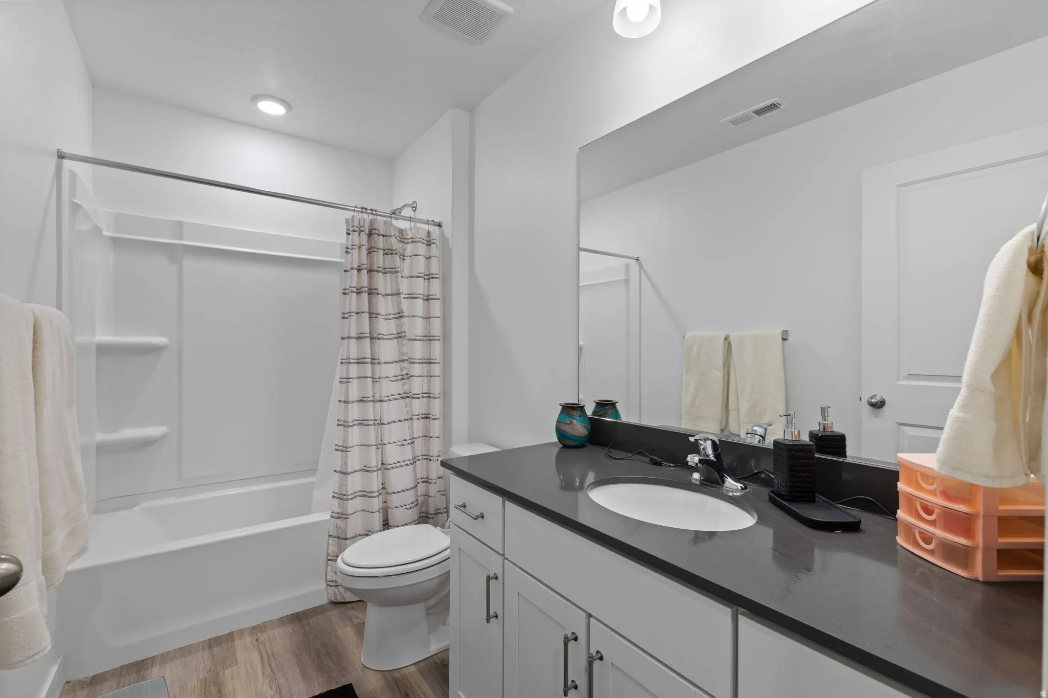Full bath featuring vanity, dark wood finished floors, and shower / bathtub combination with curtain