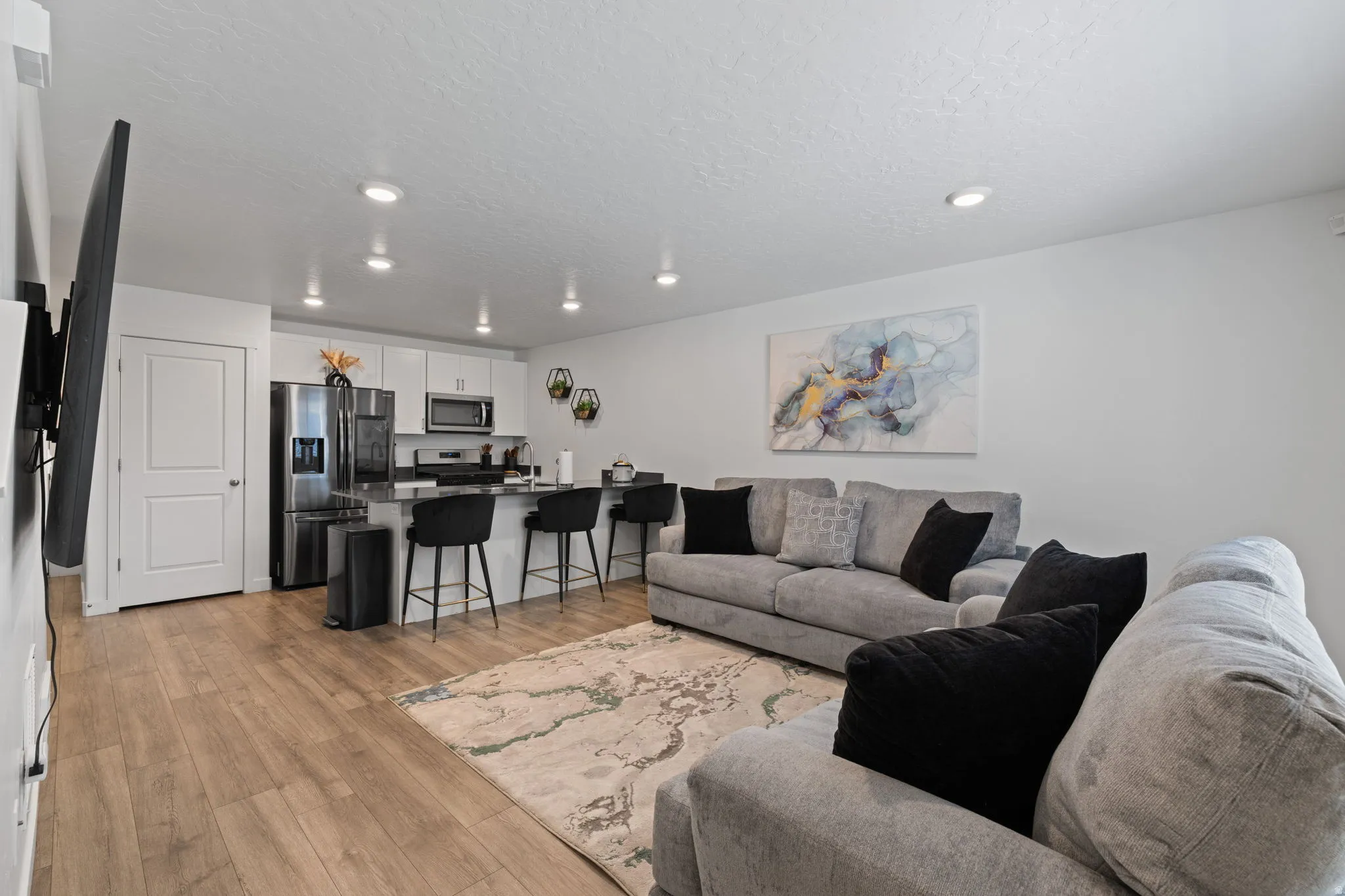 Living room with light wood-style flooring, a textured ceiling, and recessed lighting