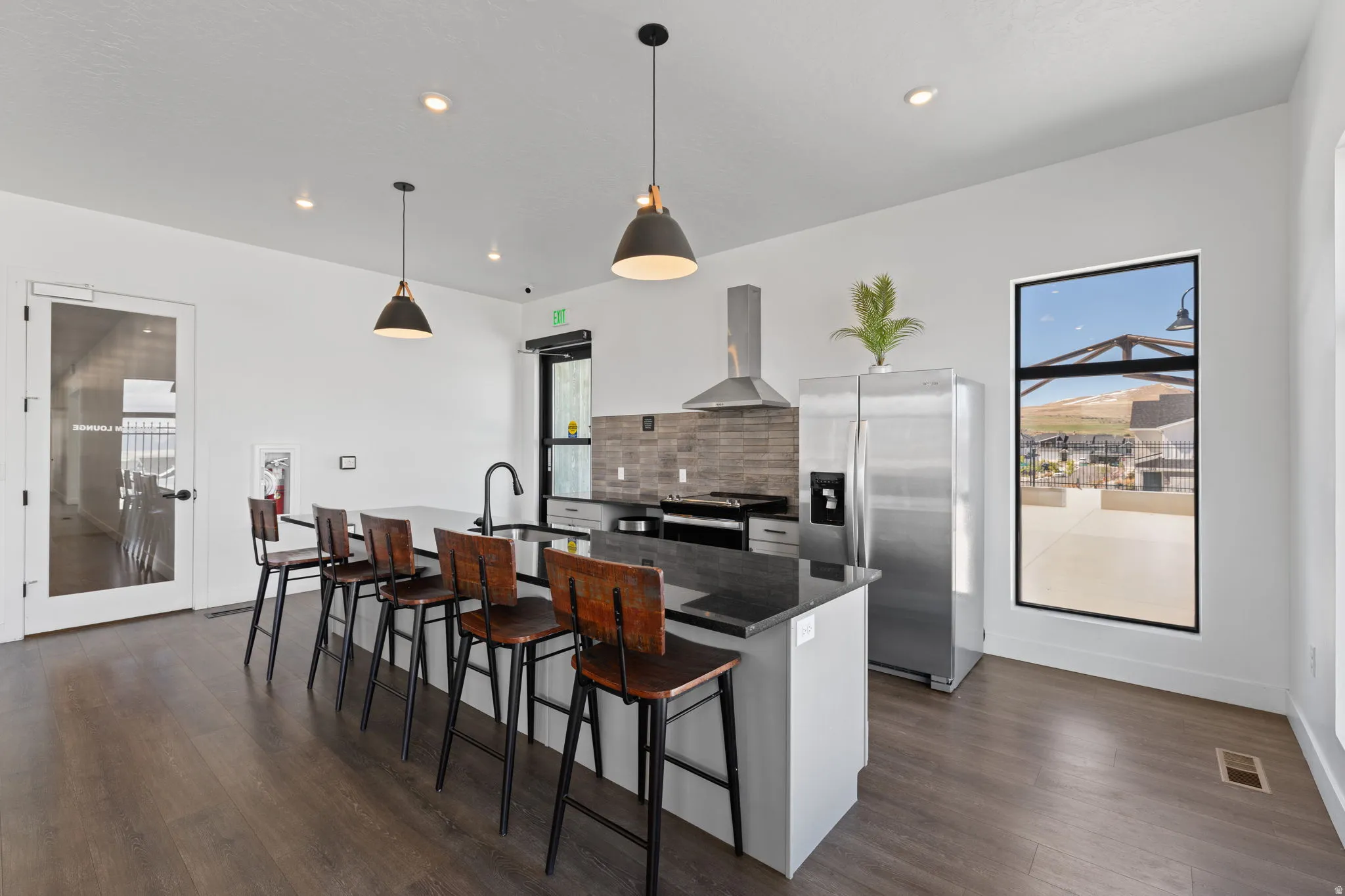 Kitchen with stainless steel appliances, a breakfast bar area, a center island with sink, extractor fan, and hanging light fixtures