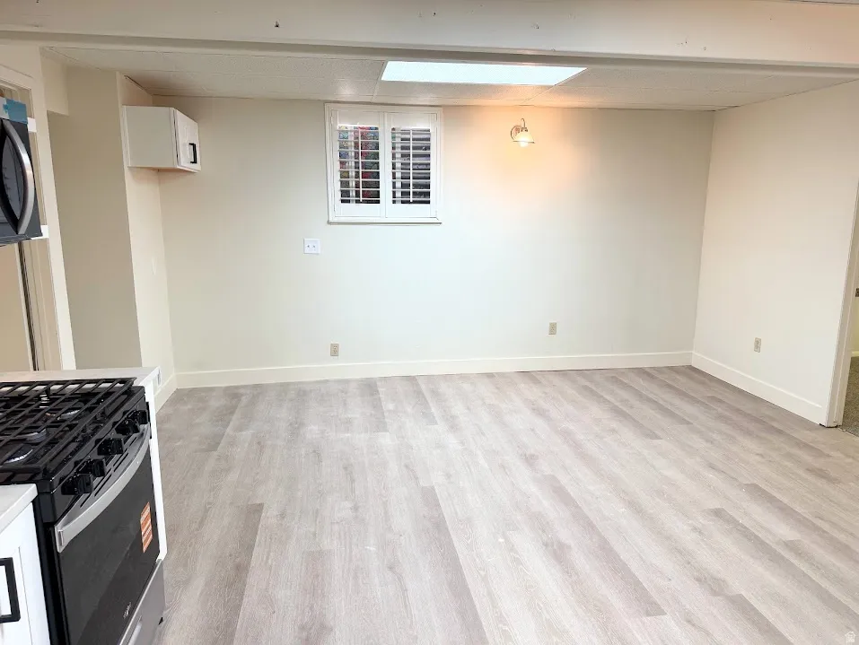 Open concept living area with wood-finish flooring, recessed lighting, and a window with plantation shutters