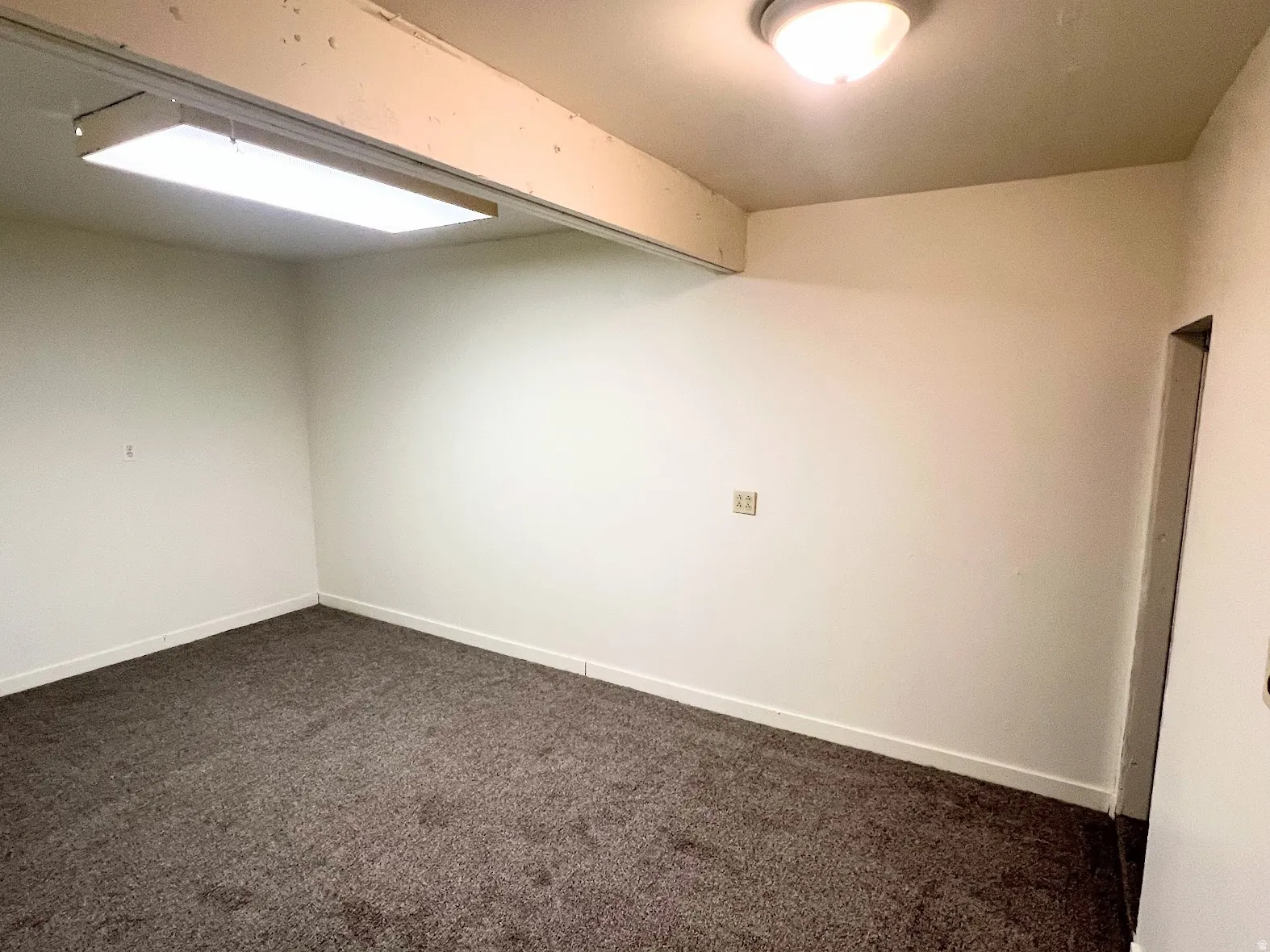 Empty room featuring dark colored carpet and baseboards