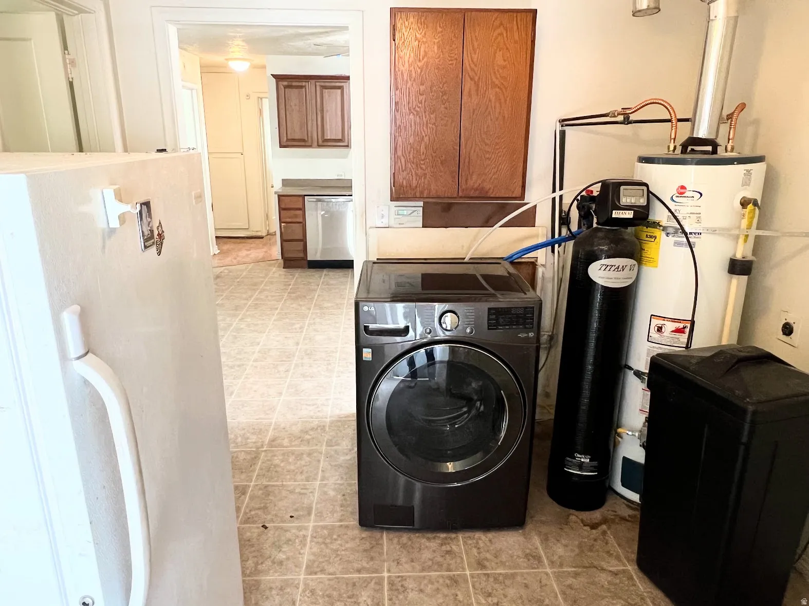 Laundry room featuring washer / clothes dryer, cabinet space, and strapped water heater