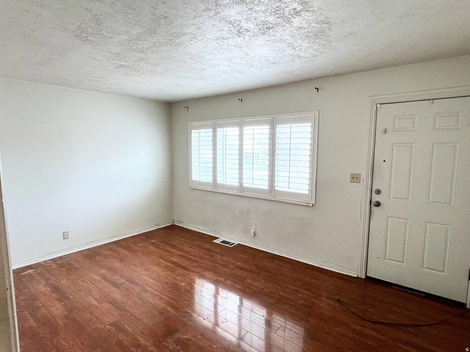 Entryway with a textured ceiling and dark wood-style flooring