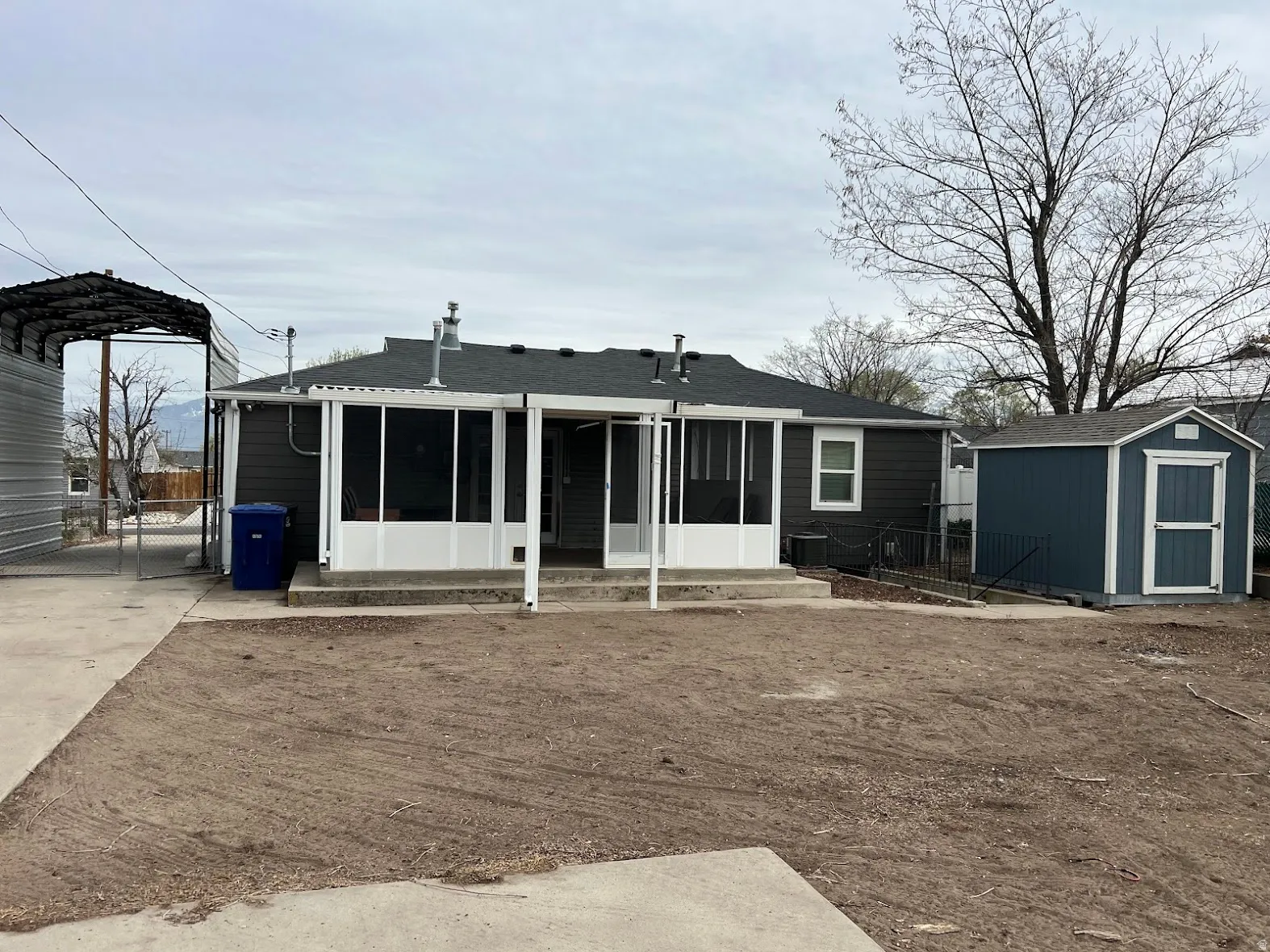 Rear view of property with a shingled roof and a shed