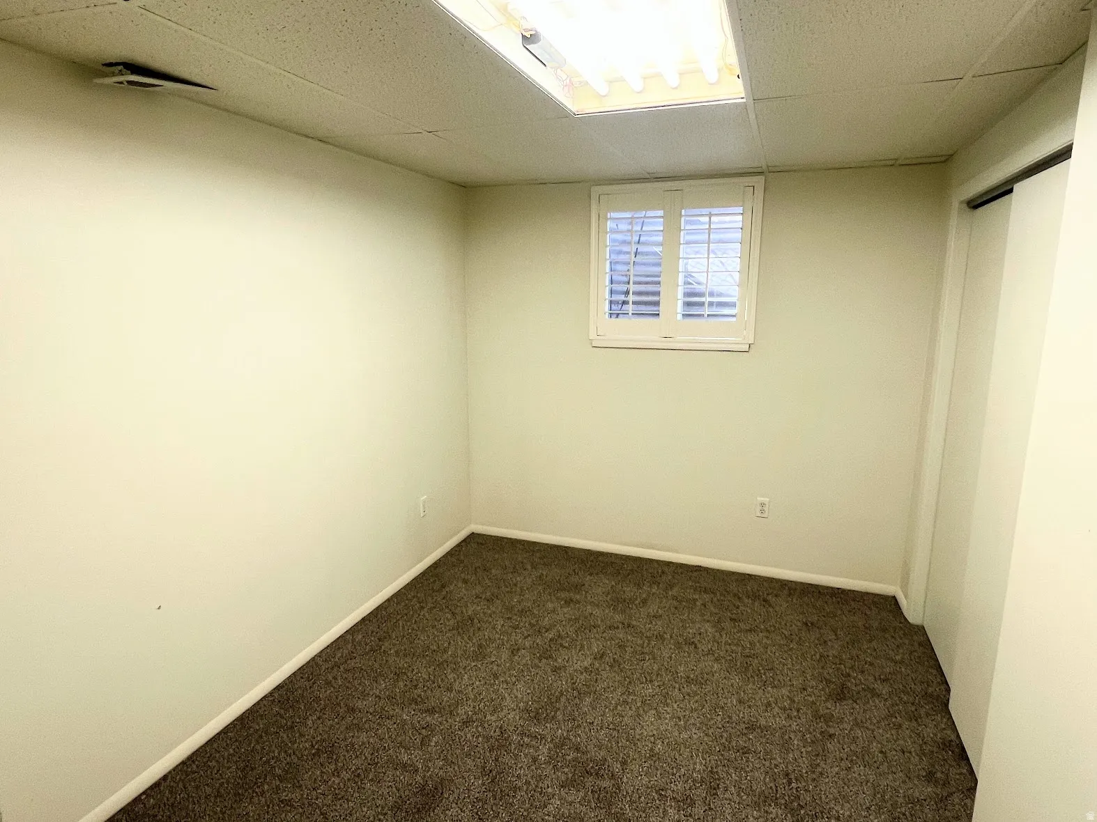 Empty room with dark carpet and a paneled ceiling