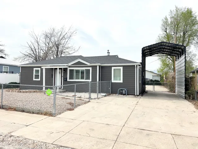 View of front of home featuring a gate, a fenced front yard, a carport, driveway, and a shingled roof