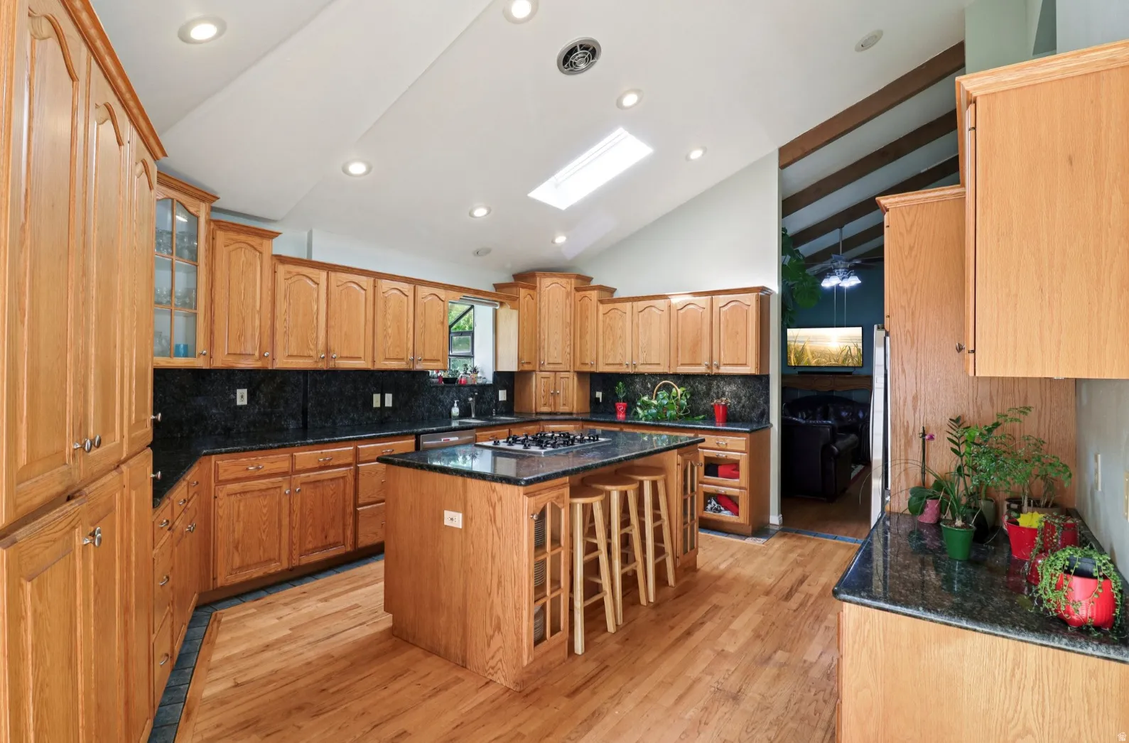 Kitchen featuring a kitchen breakfast bar, dark stone counters, a skylight, tasteful backsplash, and lofted ceiling