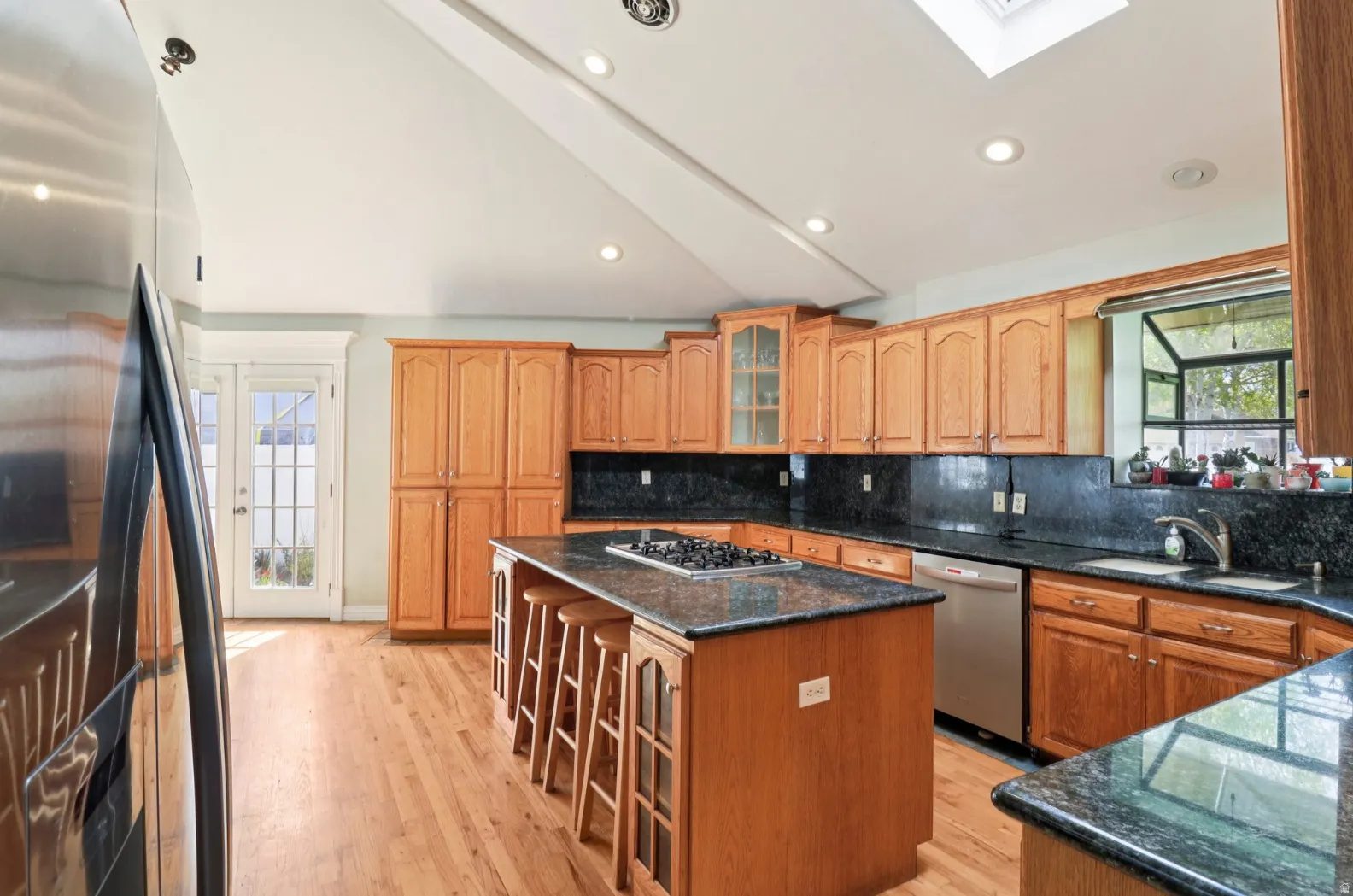 Kitchen with stainless steel appliances, glass insert cabinets, a kitchen bar, a kitchen island, and dark stone counters