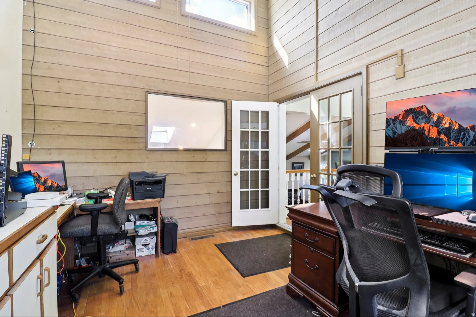 Office featuring wood walls, a high ceiling, and light wood-style floors