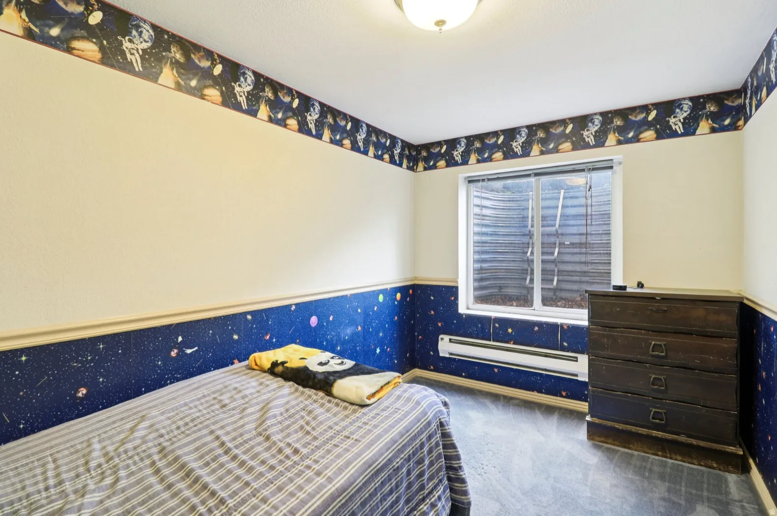 Bedroom with a baseboard radiator, dark carpet, and wainscoting