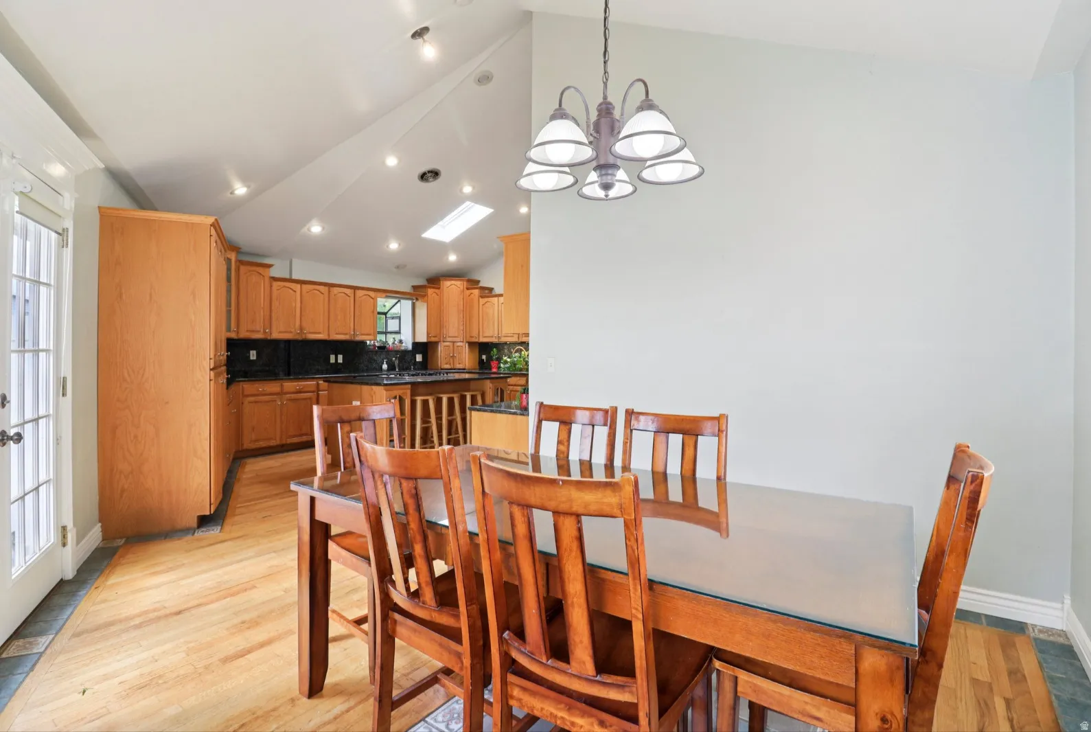 Dining room featuring light wood finished floors, lofted ceiling, and a chandelier
