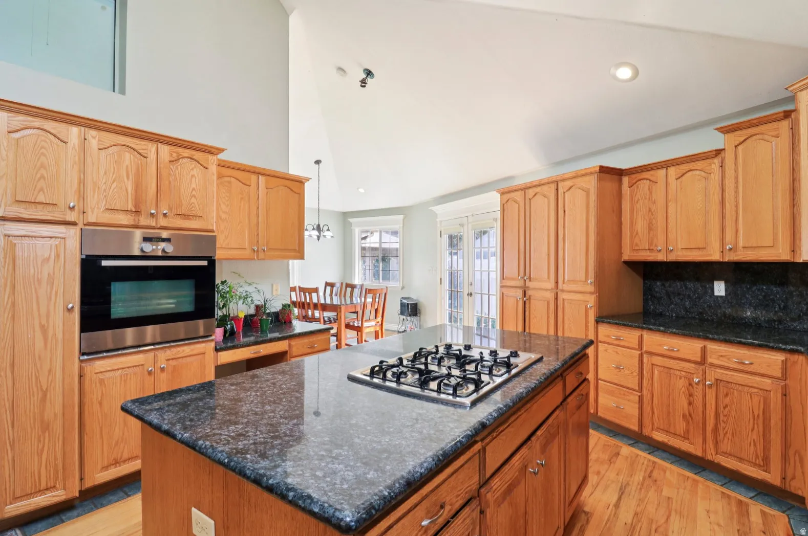 Kitchen featuring a center island, stainless steel appliances, light wood-style flooring, dark stone countertops, and lofted ceiling