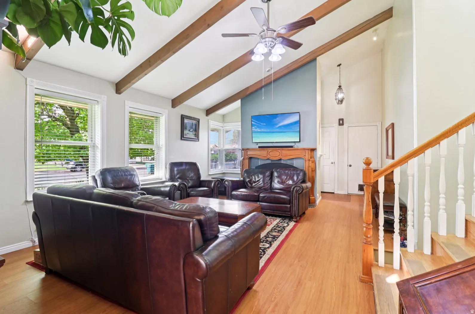 Living area with light wood-type flooring, a fireplace, lofted ceiling, and a ceiling fan