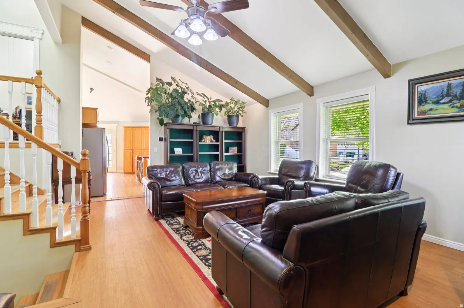 Living area with lofted ceiling, a ceiling fan, and light wood-style floors