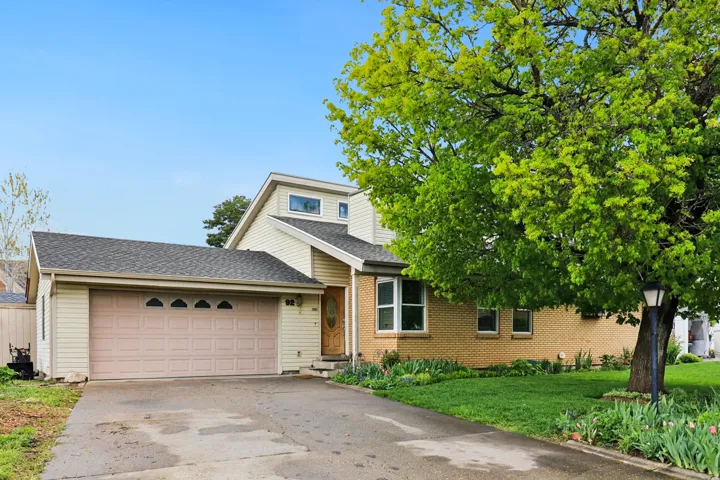 View of front of home with roof with shingles, an attached garage, concrete driveway, a front yard, and brick siding