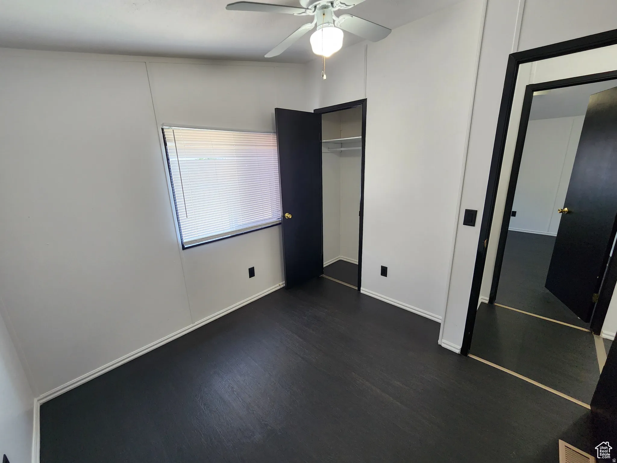 Unfurnished bedroom featuring dark wood-style flooring and a ceiling fan