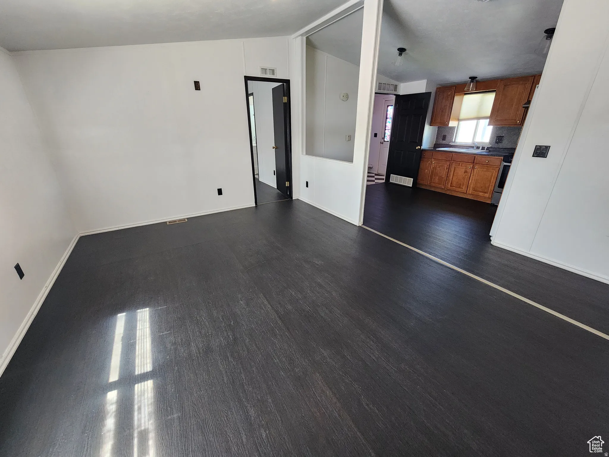 Unfurnished living room featuring vaulted ceiling and dark wood-type flooring