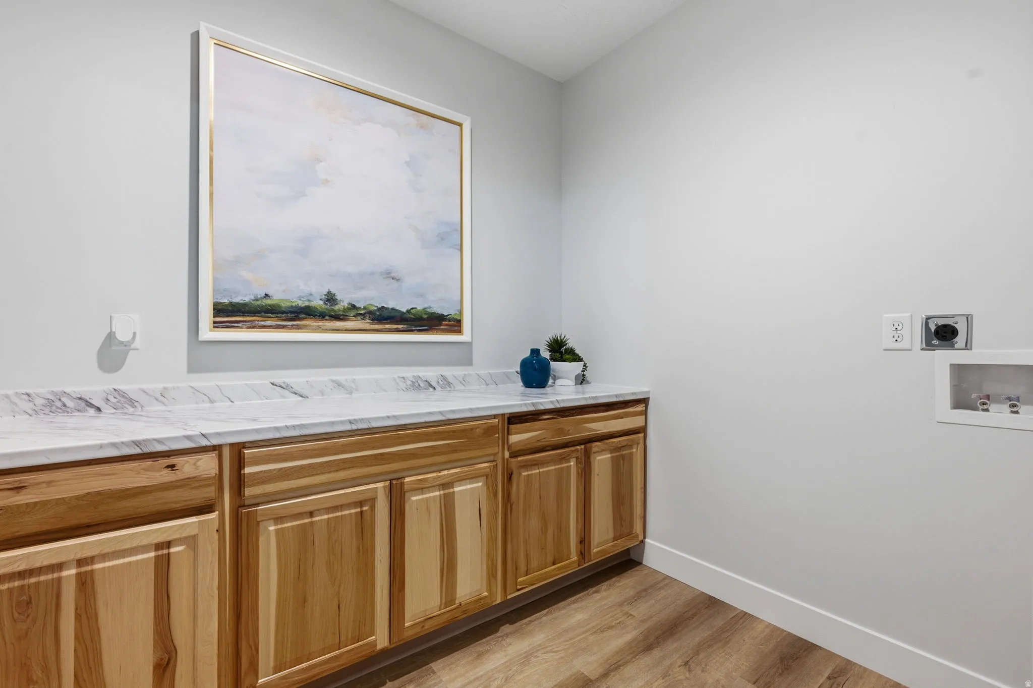 Laundry room featuring light wood-style floors, washer hookup, and cabinet space
