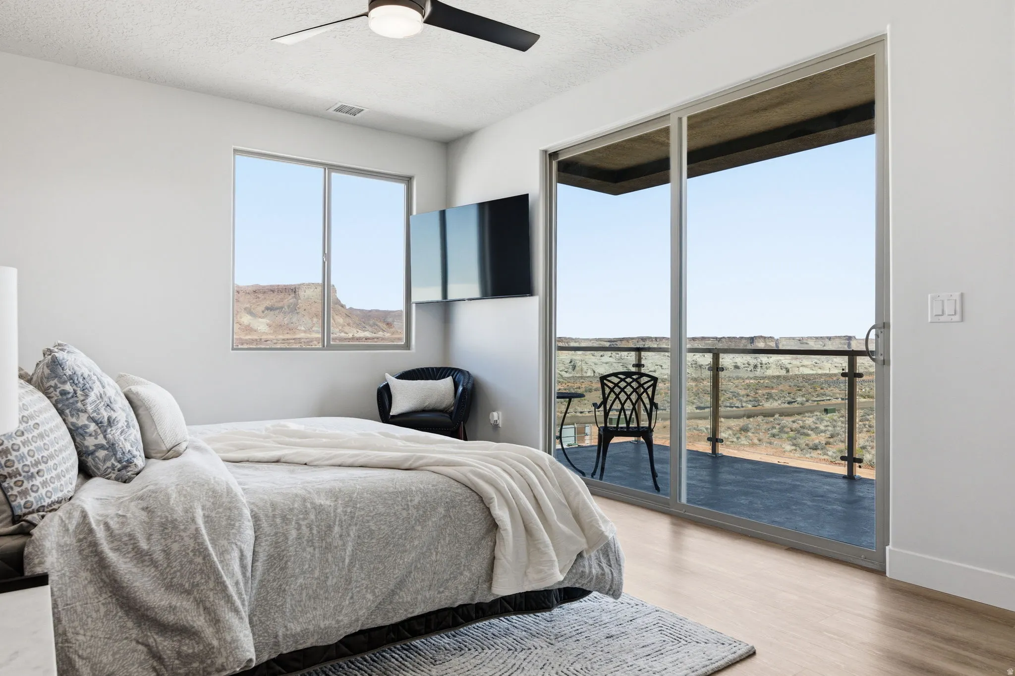 Bedroom with ceiling fan, access to outside, a textured ceiling, and light wood-style floors