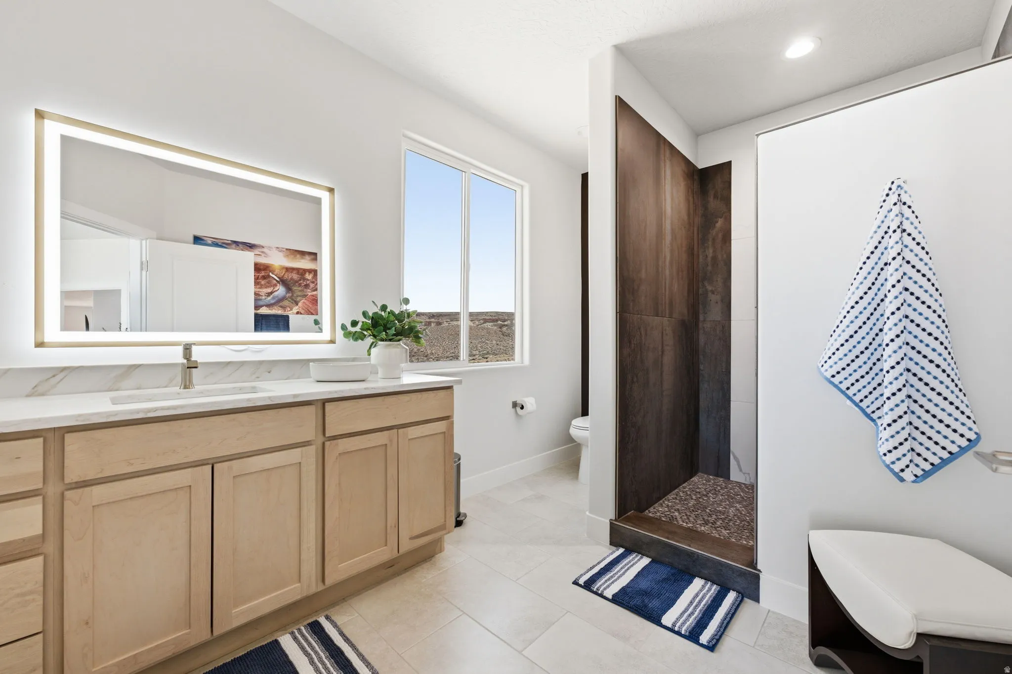 Bathroom with vanity, a tile shower, and light tile patterned floors