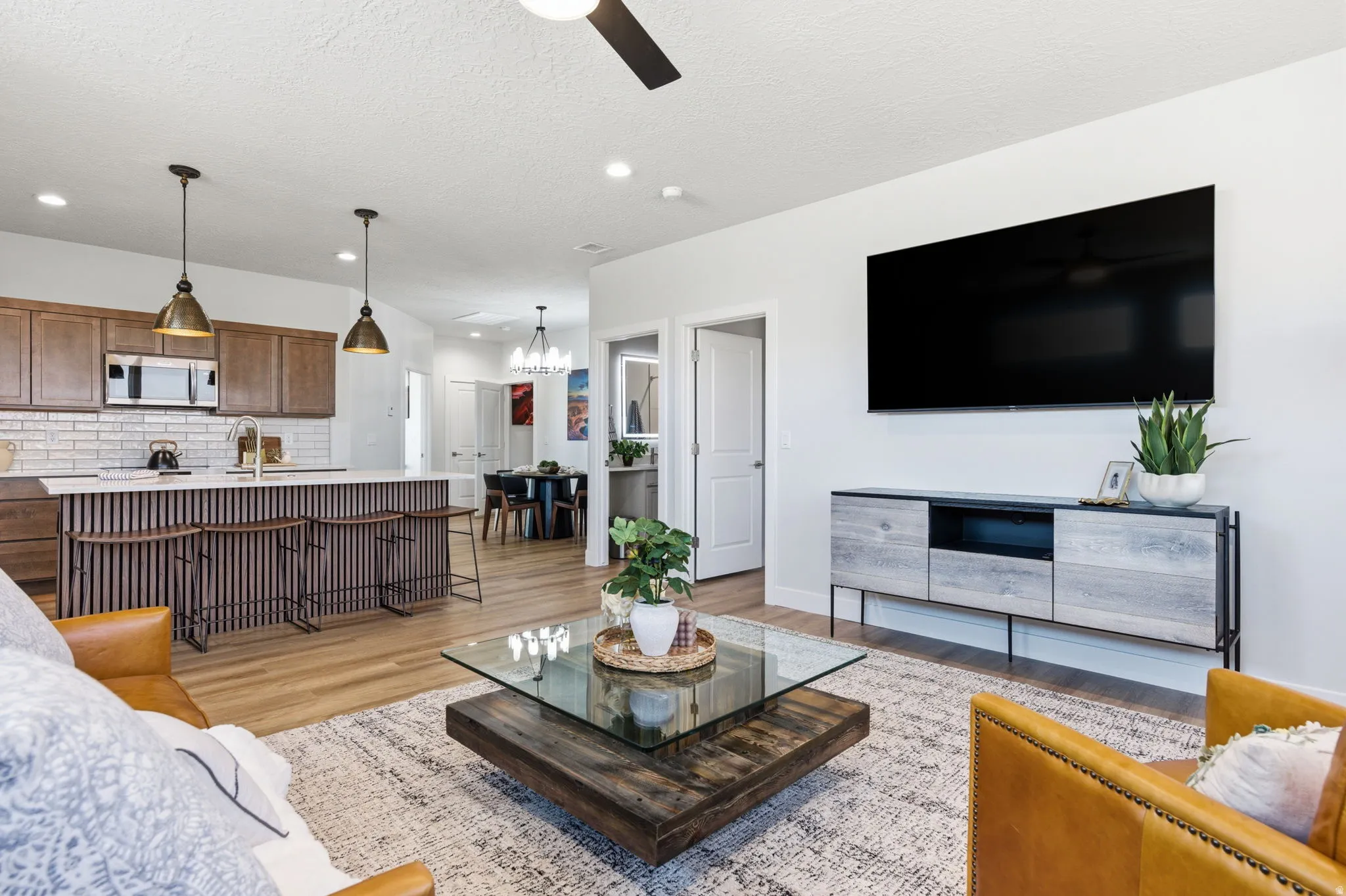 Living area featuring ceiling fan, light wood-style flooring, and a textured ceiling