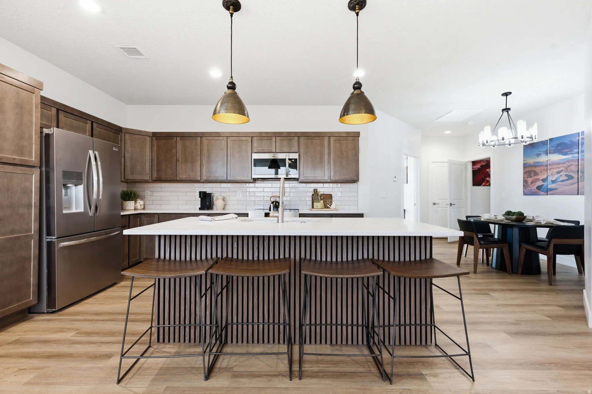 Kitchen with a kitchen bar, an island with sink, stainless steel appliances, and light wood finished floors