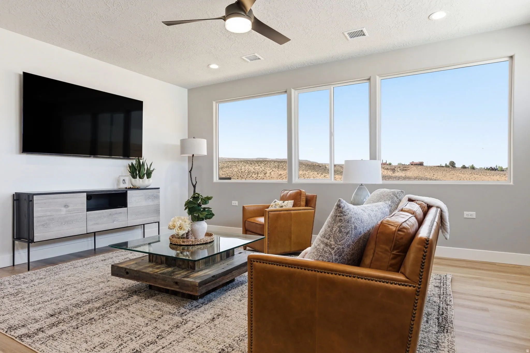 Living area featuring light wood-type flooring, a ceiling fan, a textured ceiling, and recessed lighting