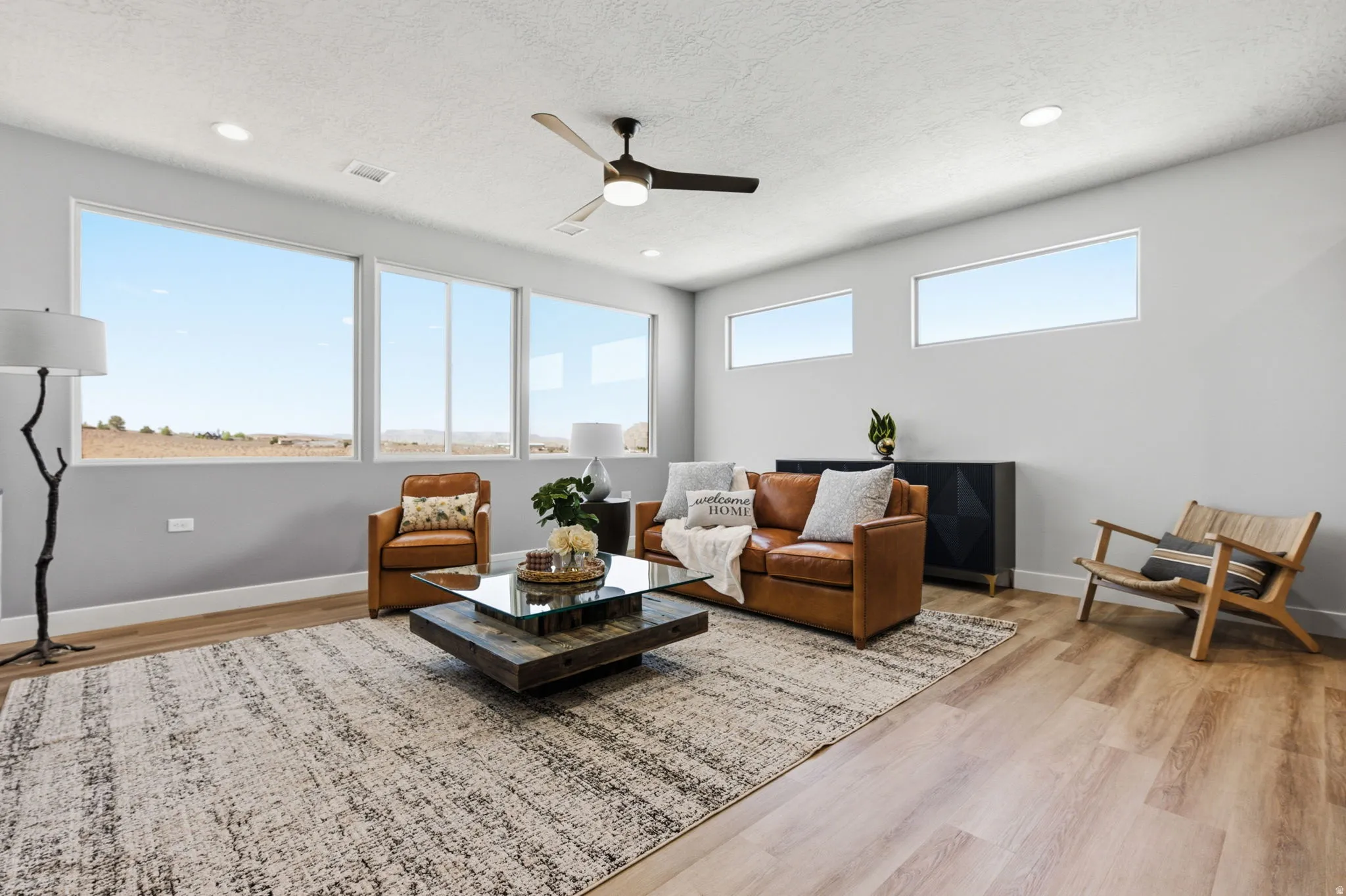 Living area featuring light wood-type flooring, ceiling fan, a textured ceiling, and recessed lighting