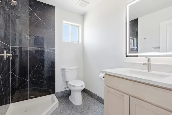 Full bathroom featuring vanity, a marble finish shower, and dark aggregate flooring