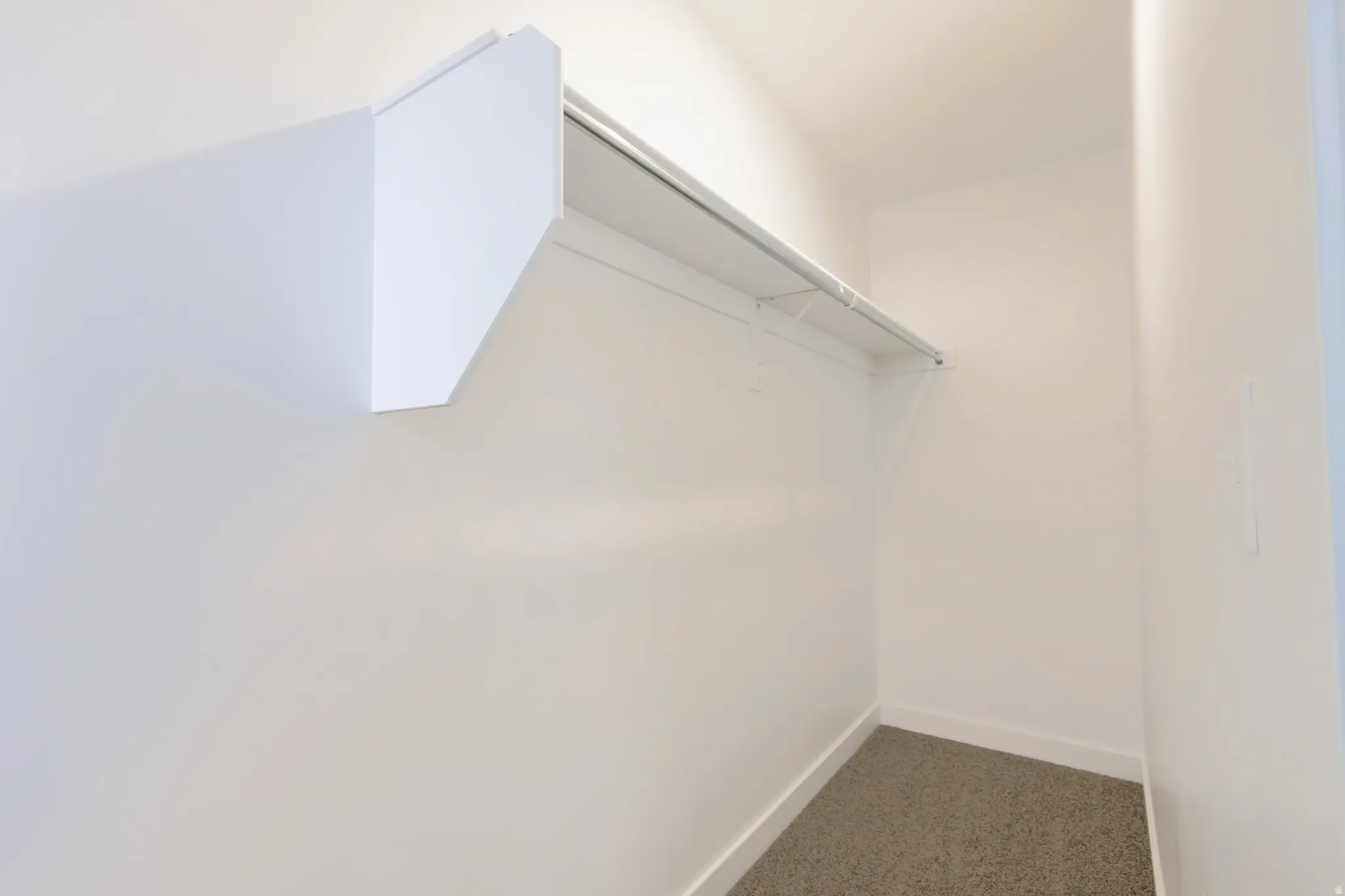 Walk in closet with dark colored carpet
