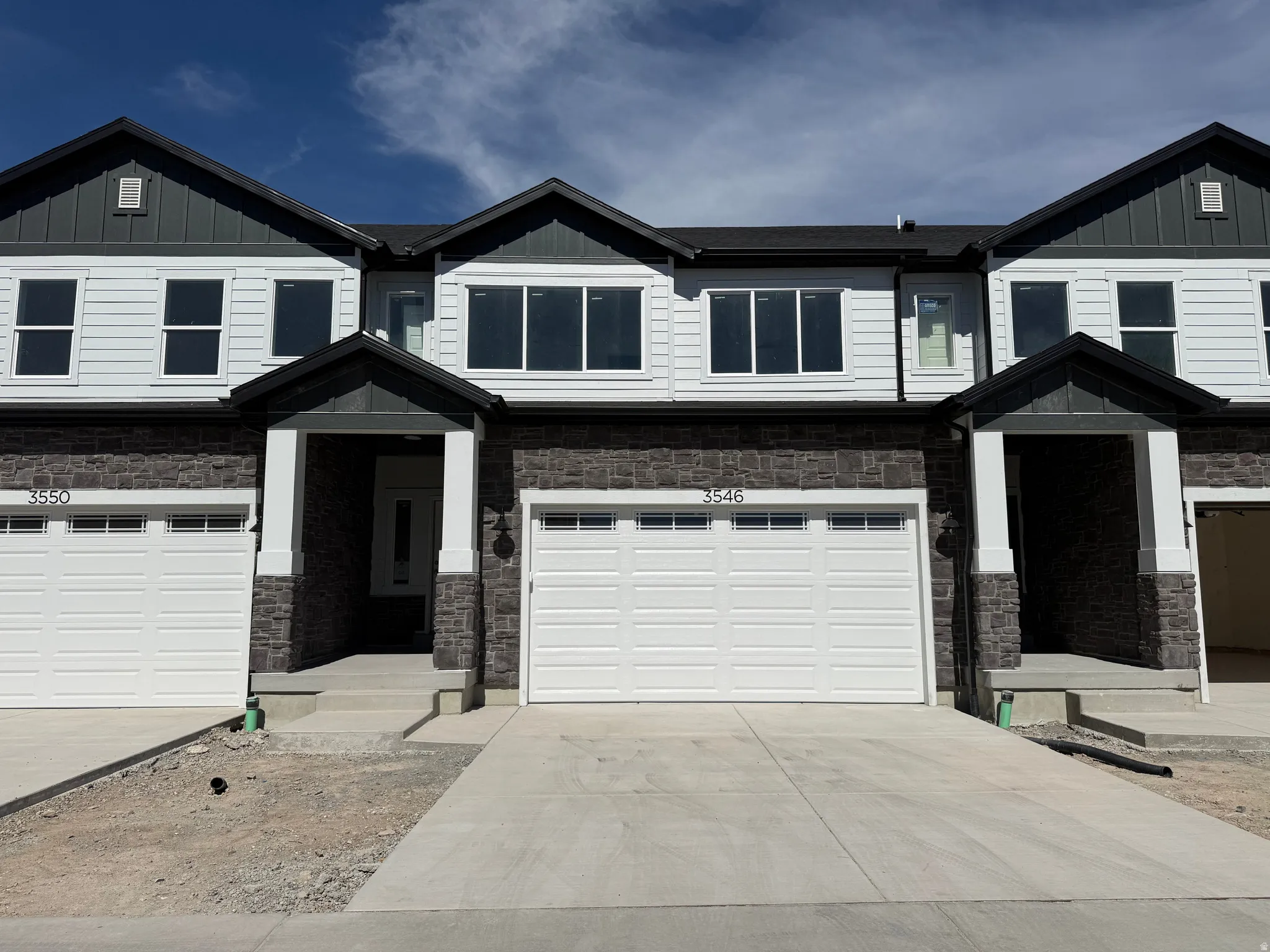 Craftsman-style home featuring stone siding, driveway, and board and batten siding
