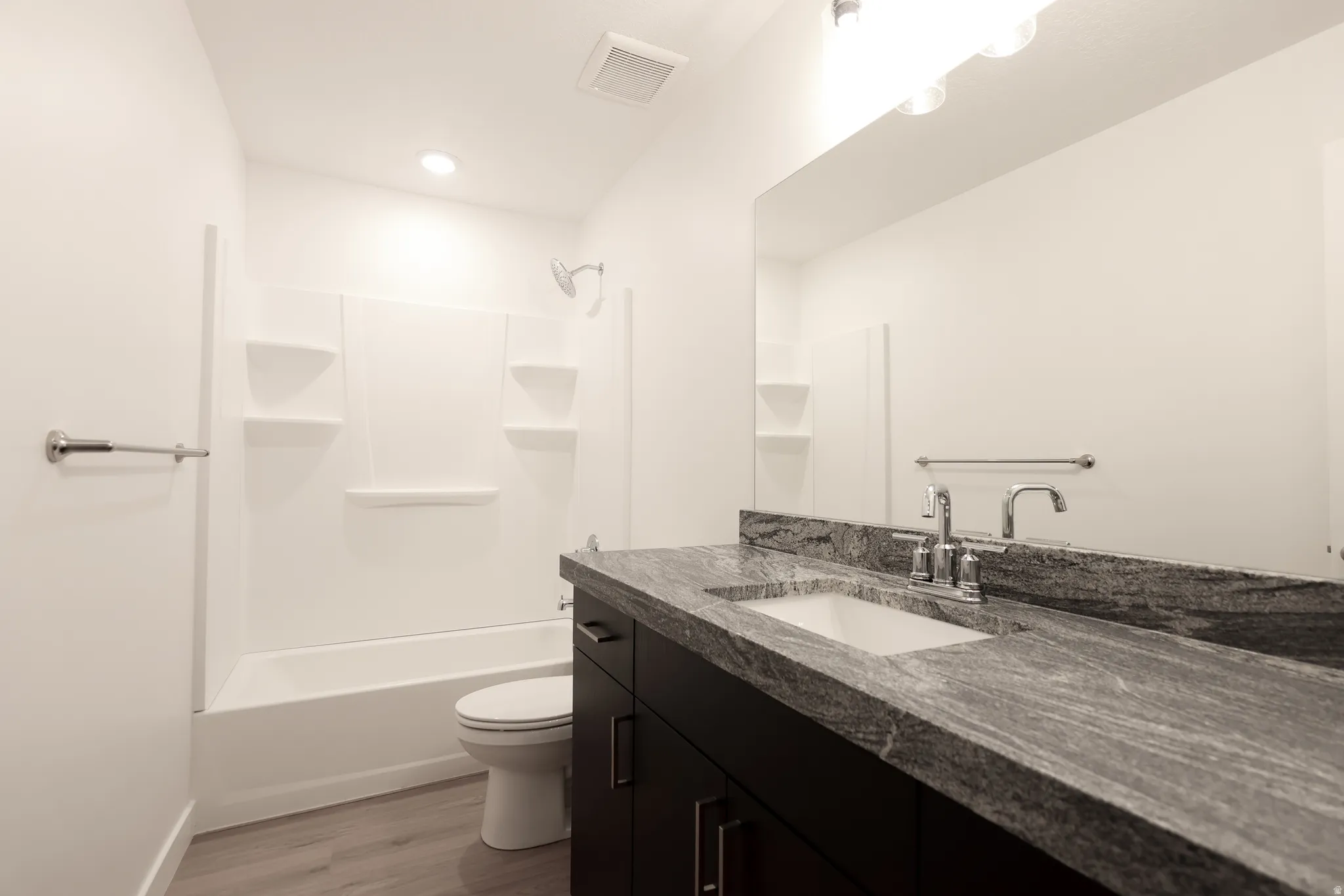 Bathroom featuring vanity, tub / shower combination, and light wood-type flooring