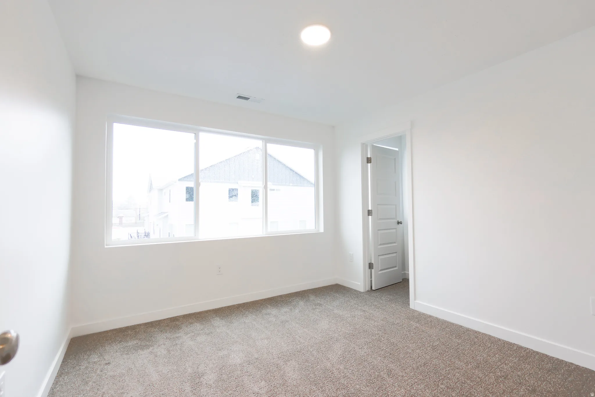 Spare room featuring light colored carpet and baseboards