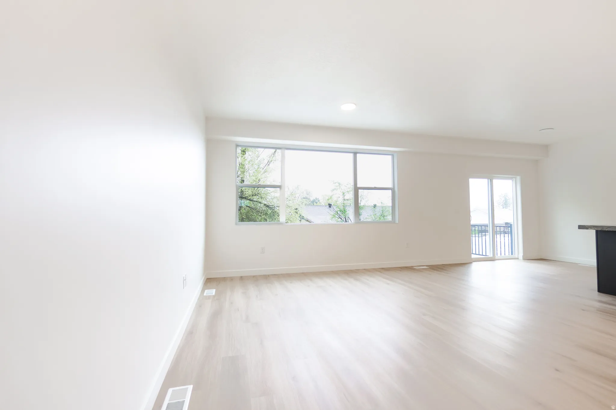 Spare room featuring light wood-type flooring, plenty of natural light, and recessed lighting