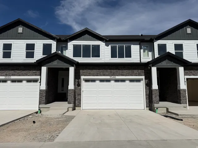 Craftsman-style home featuring stone siding, driveway, and board and batten siding